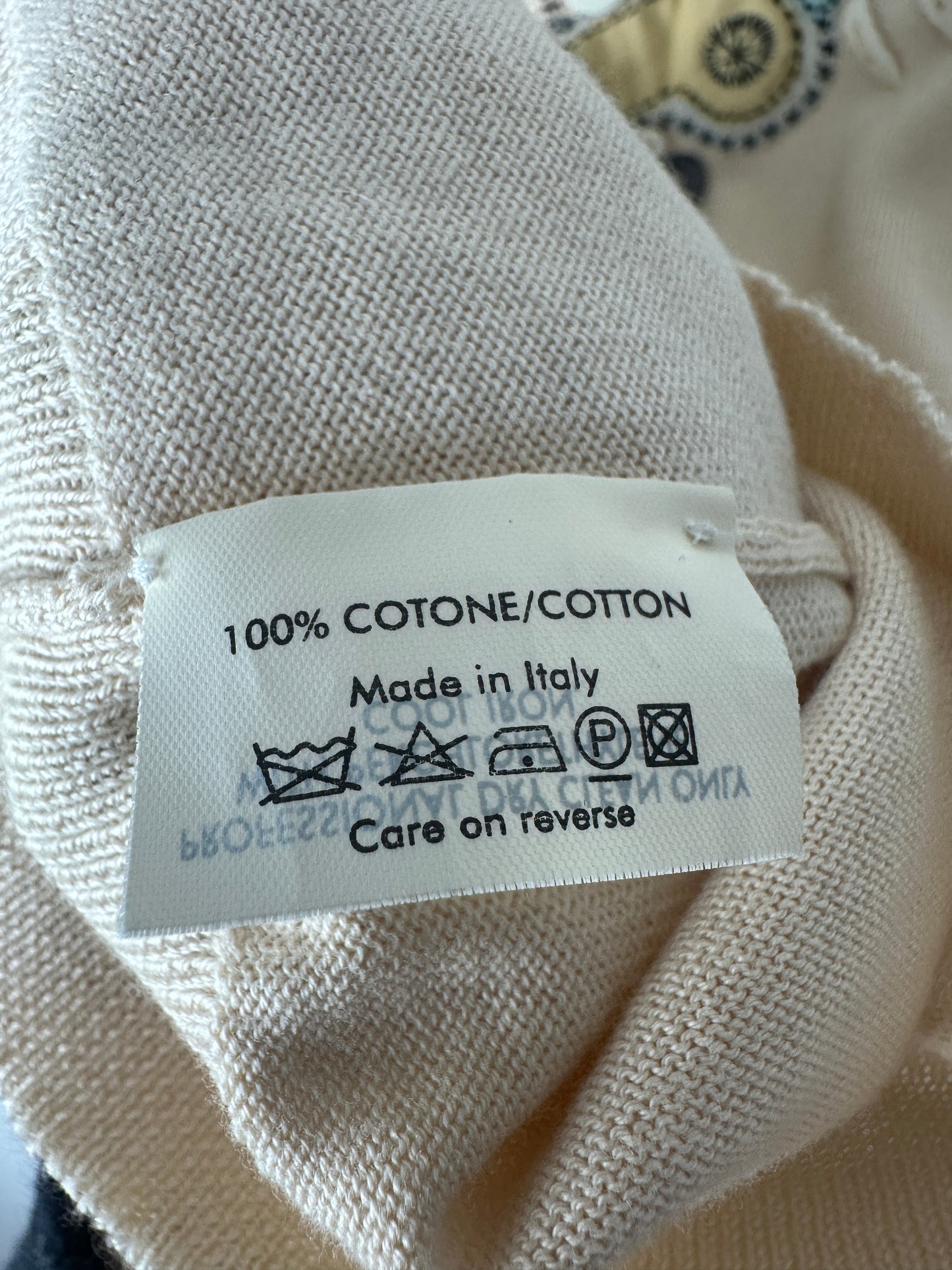 Textile label on beige fabric with care instructions and material details.