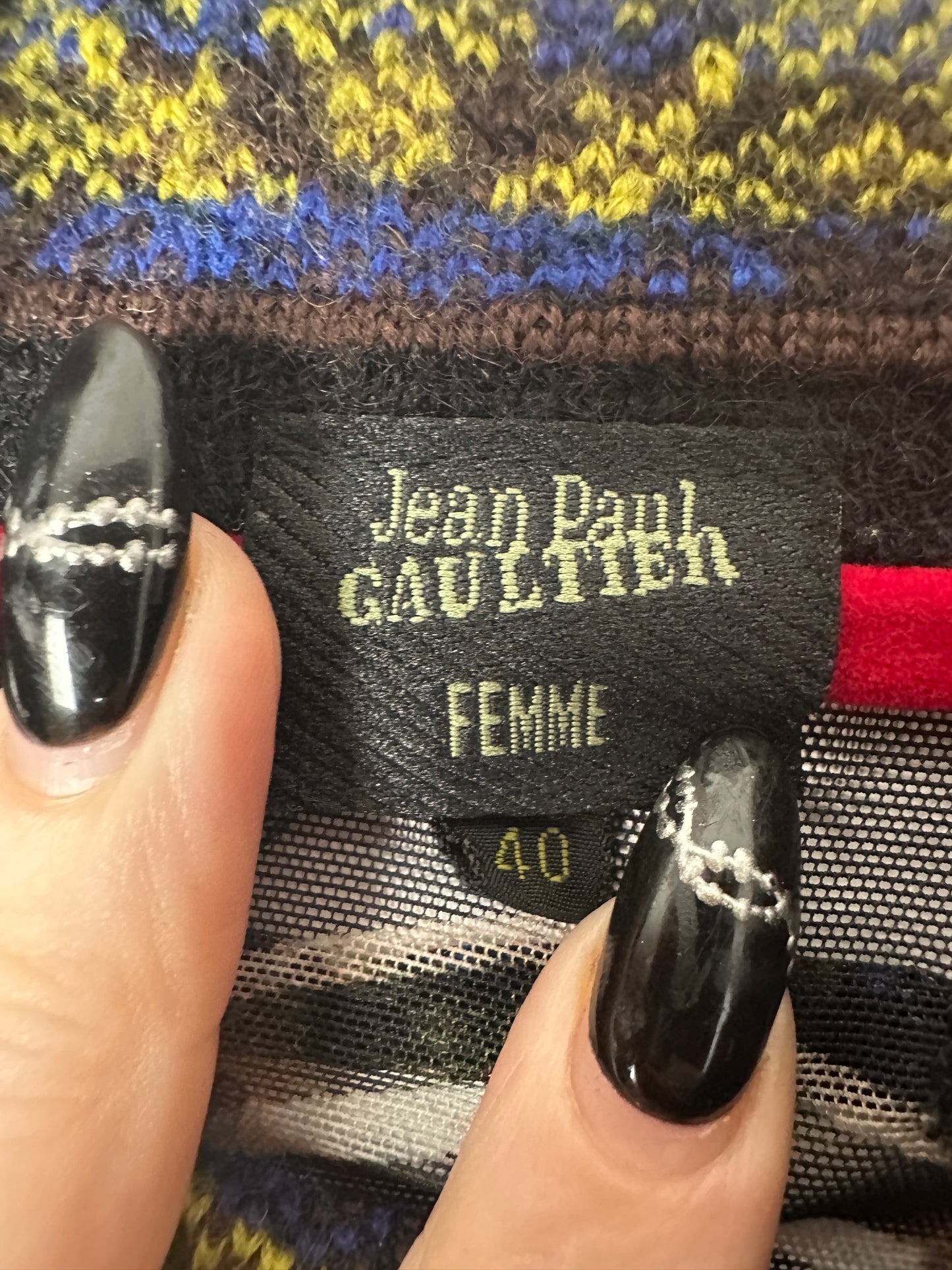 Close-up of a Jean Paul Gaultier label on a garment with a hand holding it.