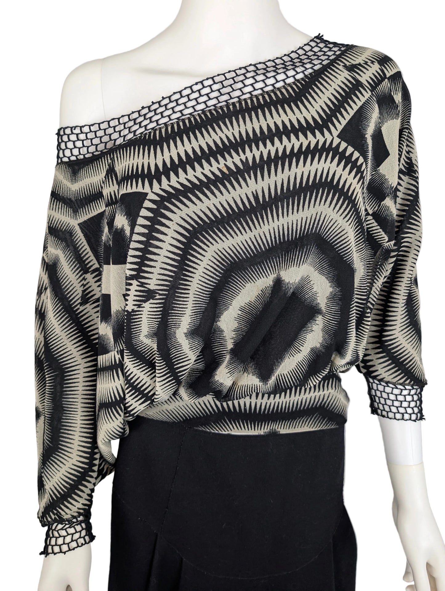 Mannequin wearing a black and white patterned top with long sleeves on a plain background