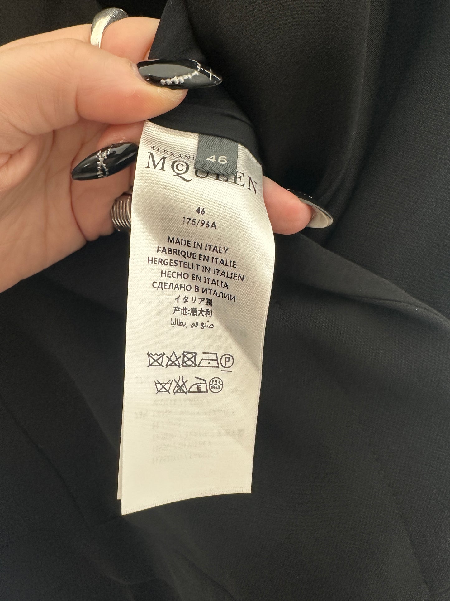 Hand holding a fashion label against a dark fabric background