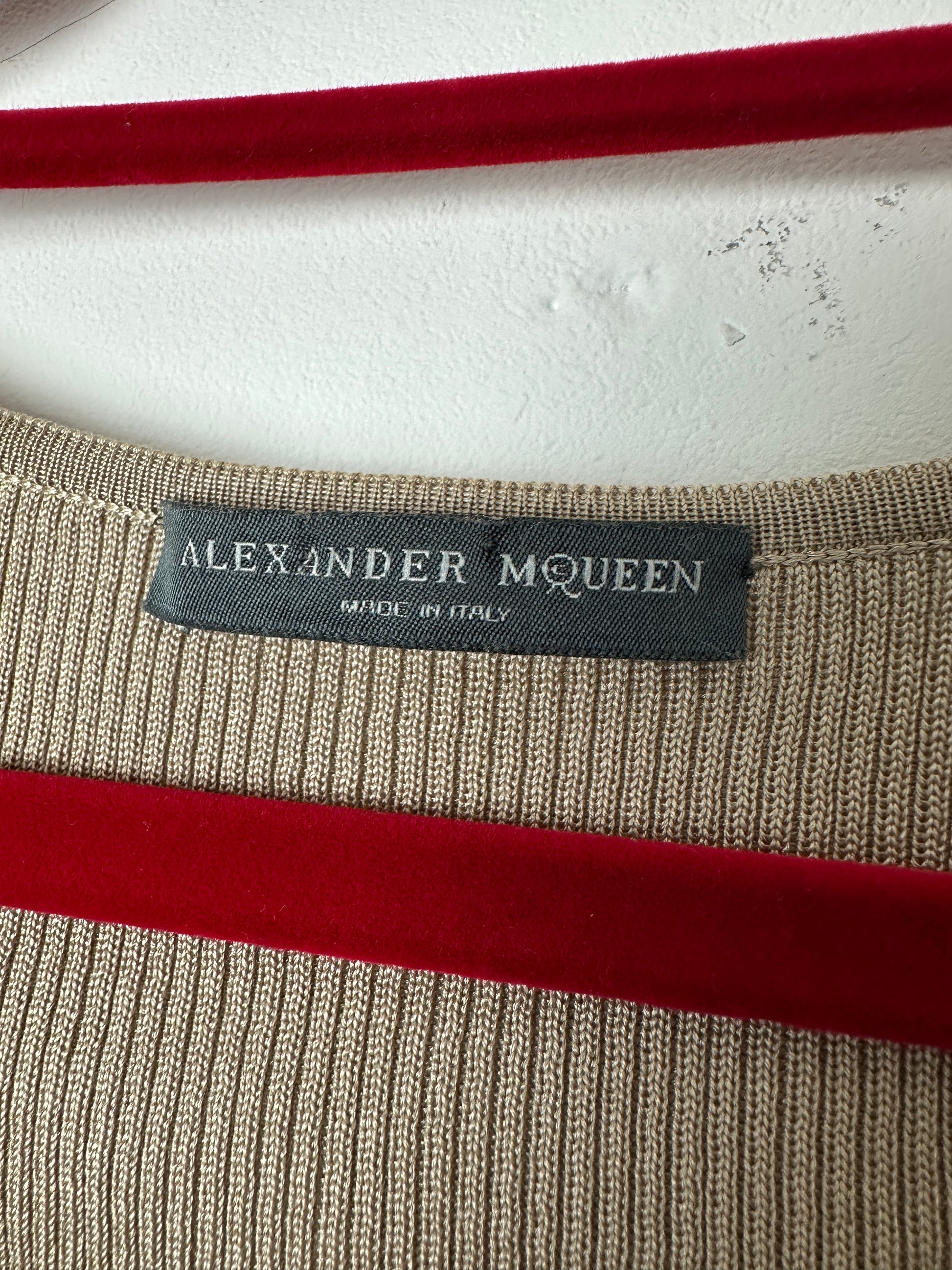 Close-up of a Alexander McQueen label on a textured fabric with red and beige colors.