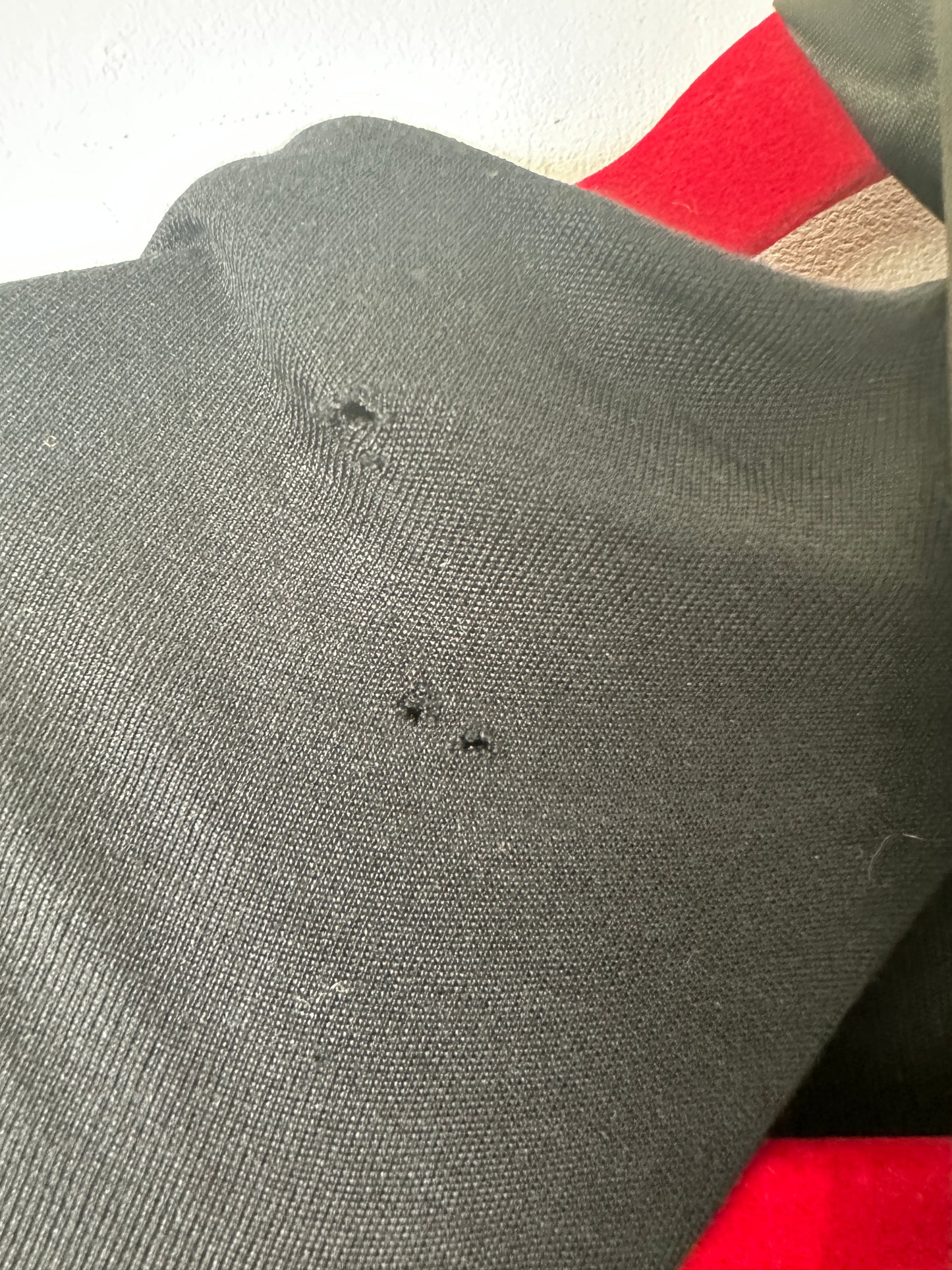 Close-up of a gray sock with small holes on a red and white background