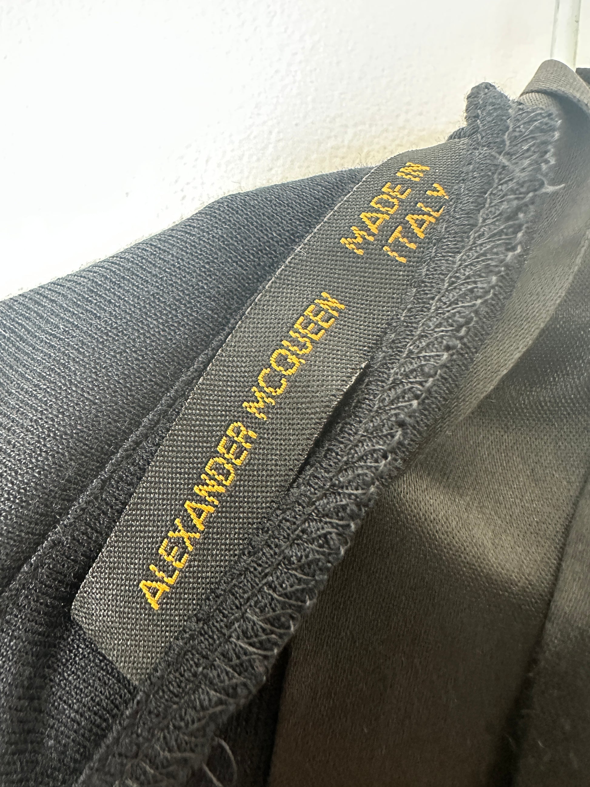 Close-up of a label on a piece of clothing with text 'Made in Italy' and 'Alexander McQueen'.