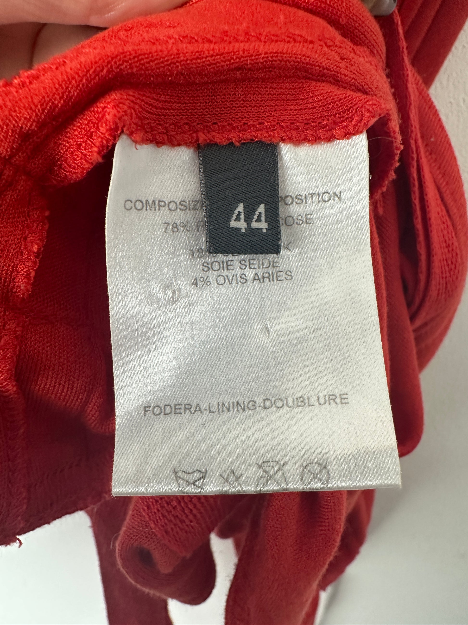 Red fabric with a label showing size 44 and material details.