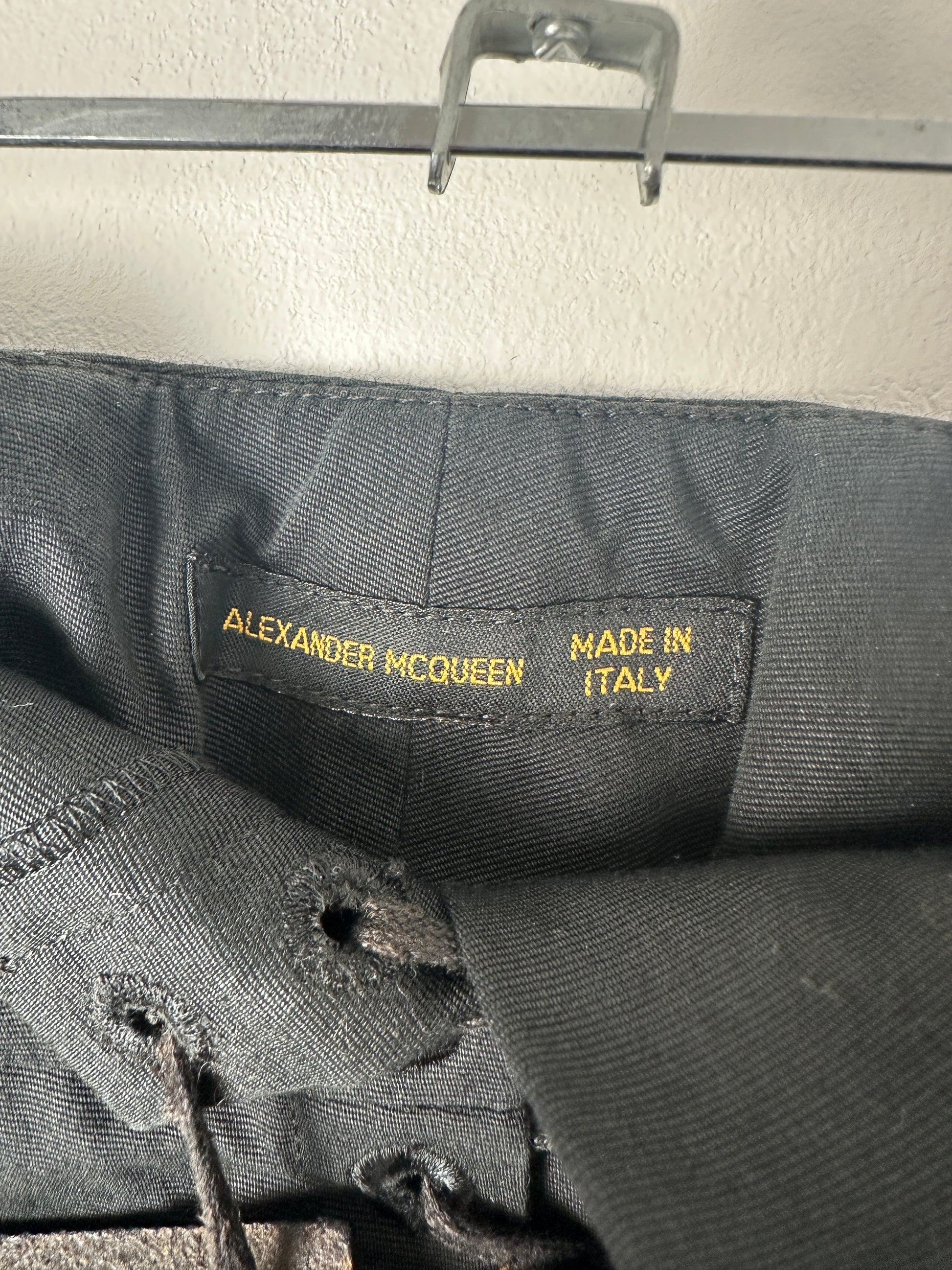 Close-up of a label on a black garment with 'Made in Italy' and 'Alexander McQueen' text.