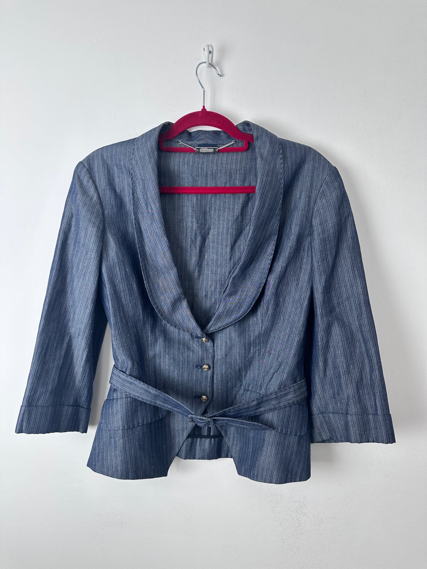 A blue-gray striped long-sleeve shirt with a tie waist and button front, hanging on a red hanger against a plain white background.