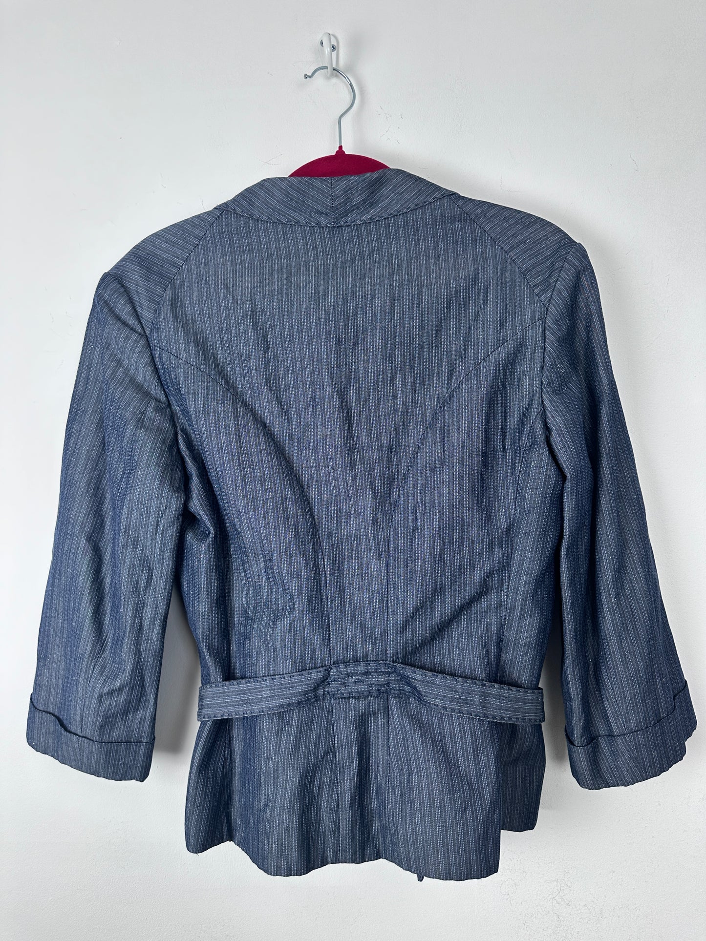 A blue pinstriped long-sleeve jacket or blazer with a matching waist tie belt, shown from the back on a white hanger against a plain white background.