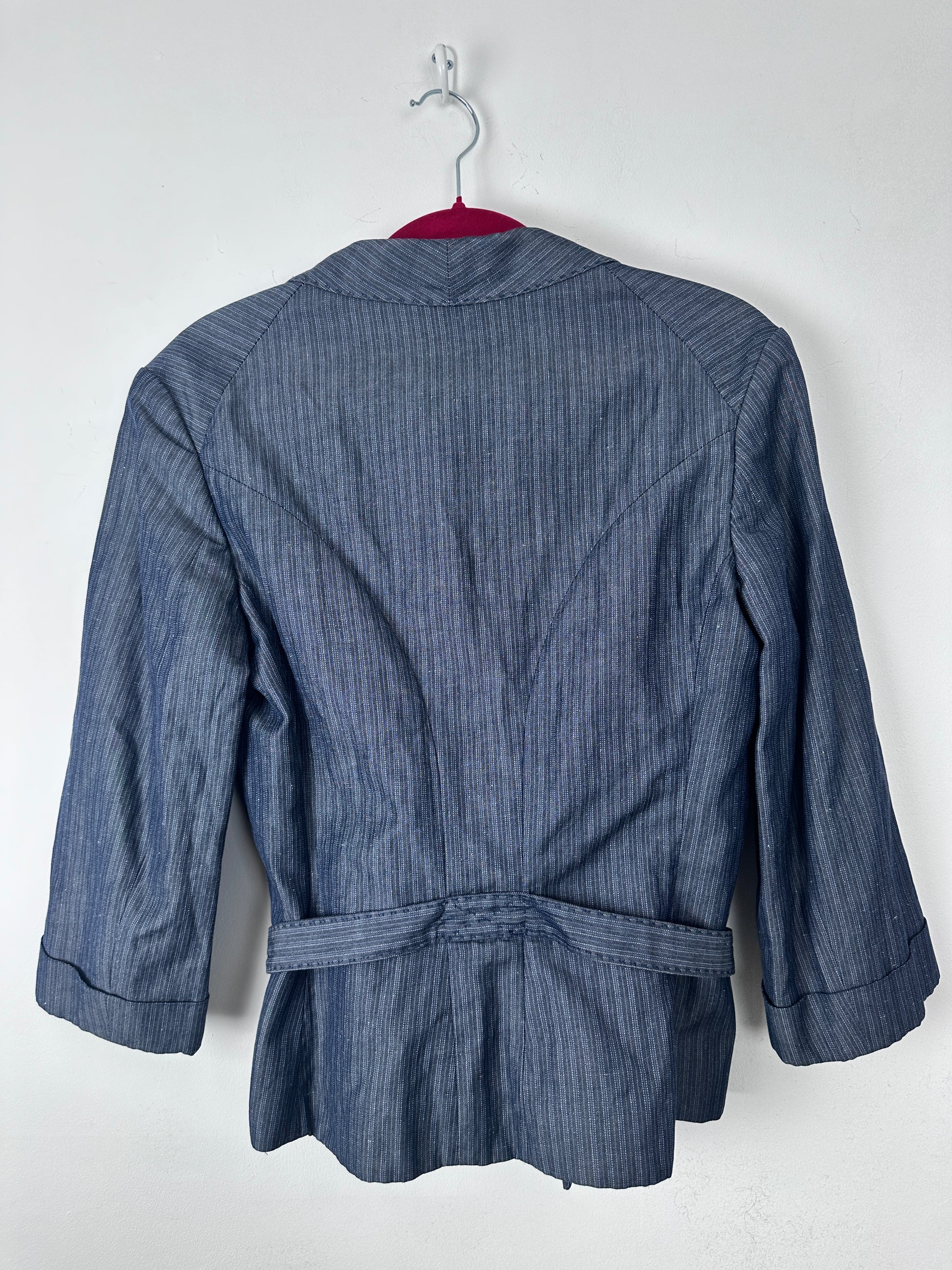 A blue pinstriped long-sleeve jacket or blazer with a matching waist tie belt, shown from the back on a white hanger against a plain white background.