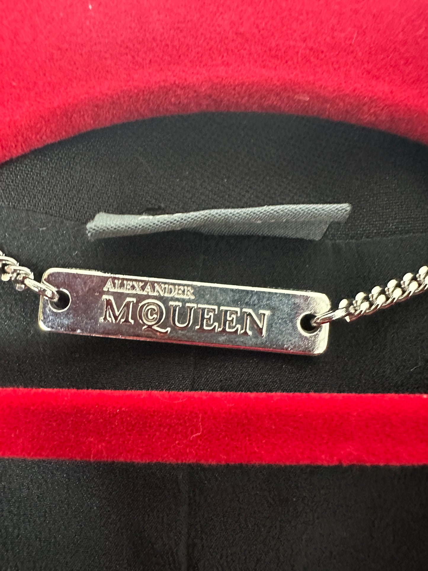 Alexander McQueen metal tag on a red and black background
