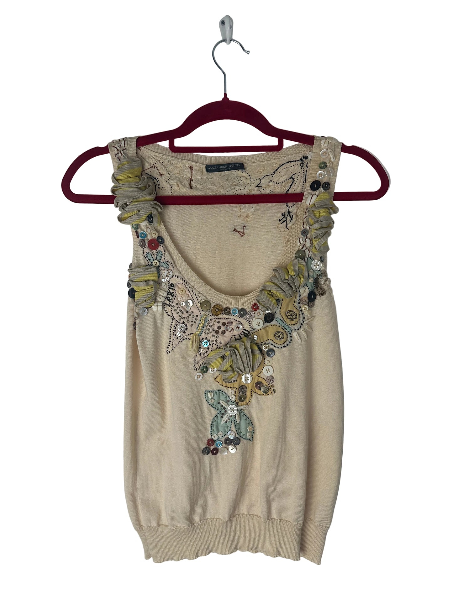 Beige top with floral embroidery on a hanger against a white background
