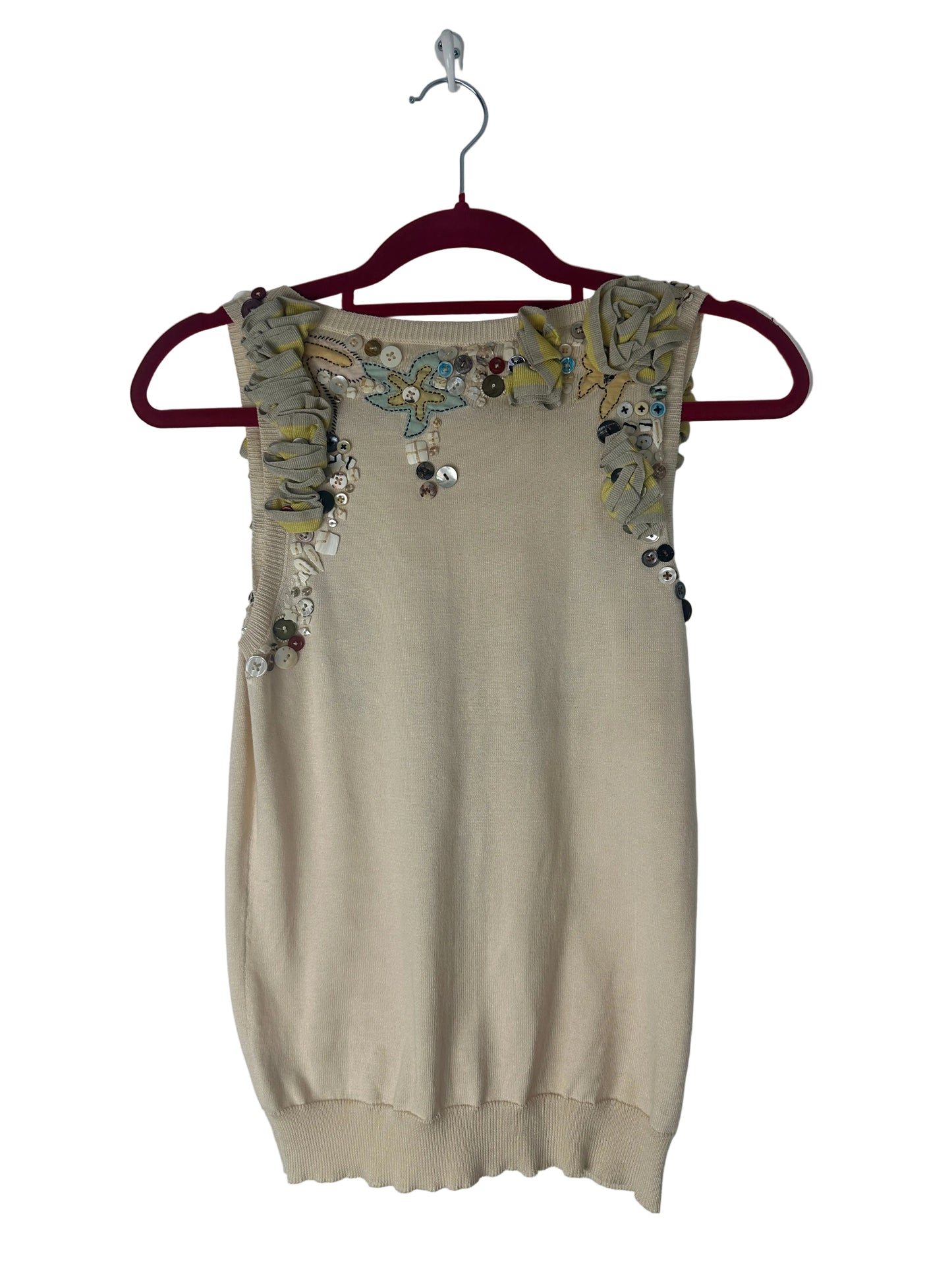Beige top with floral embroidery on a hanger against a white background