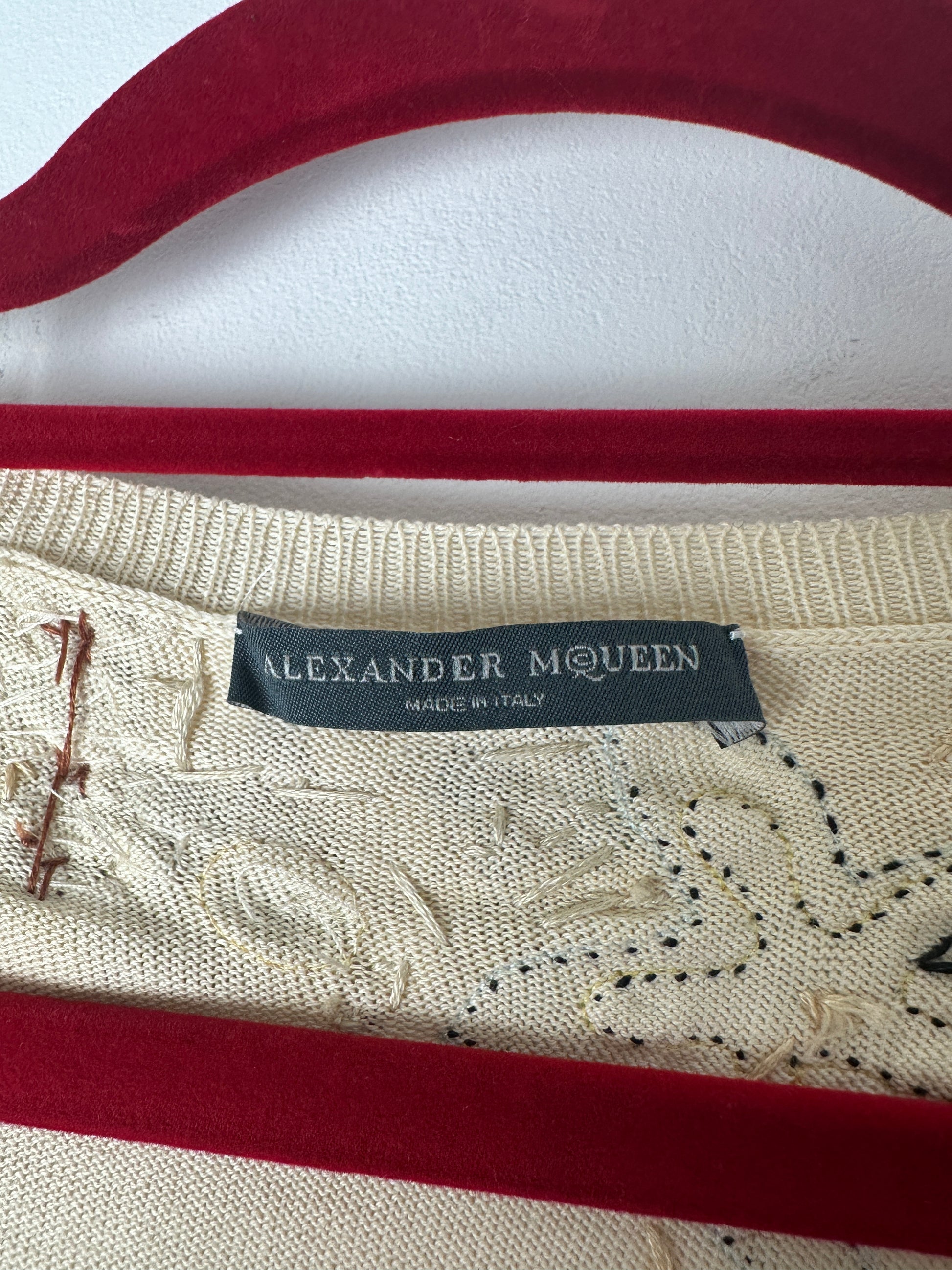 Close-up of a garment with 'Alexander McQueen' label on a red and white striped background