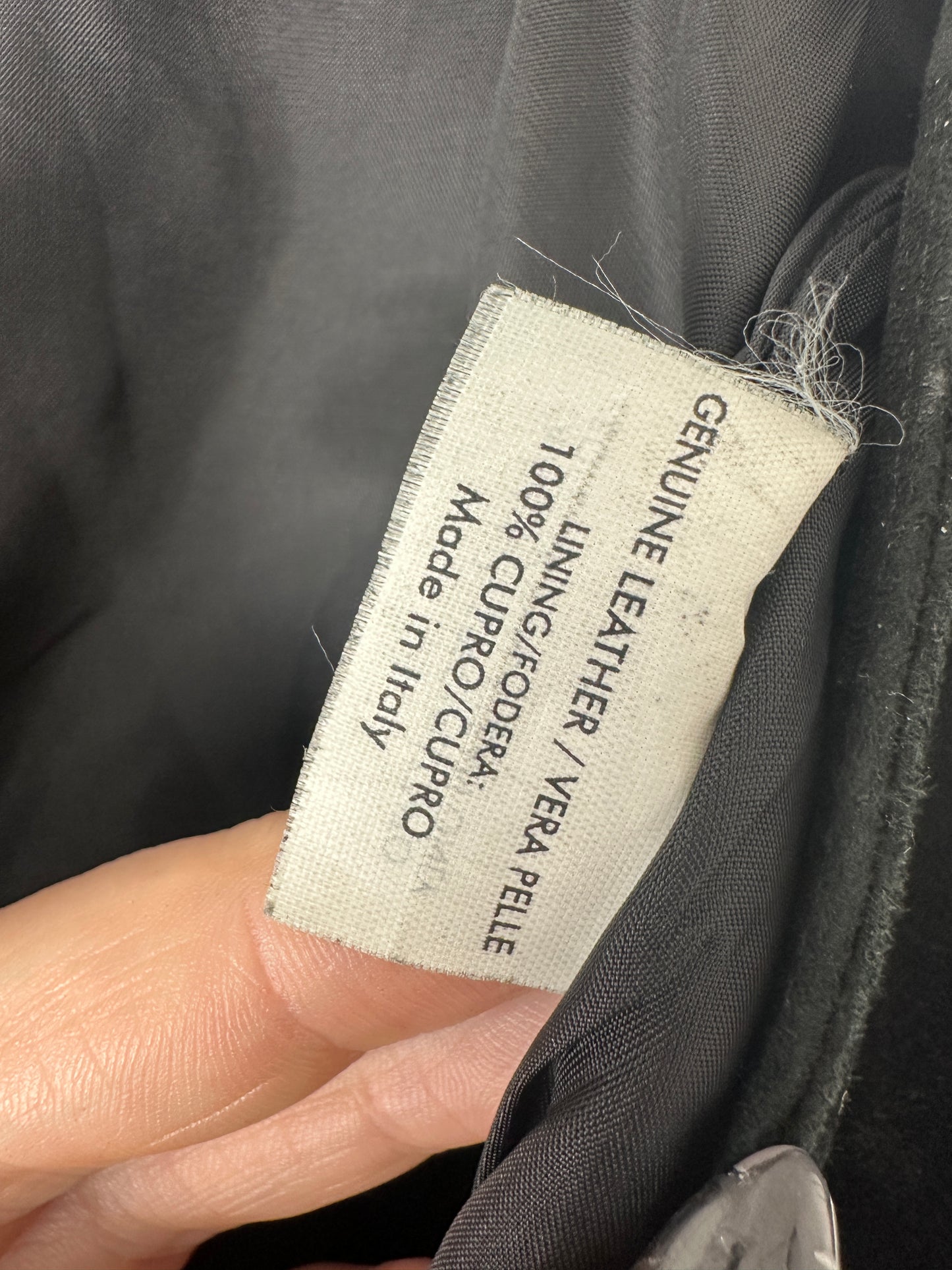 Label on a garment indicating 'Genuine Leather' and 'Made in Italy'.