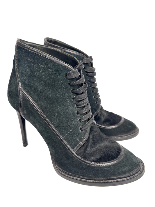 Pair of dark gray suede high-heeled shoes on a light gray background