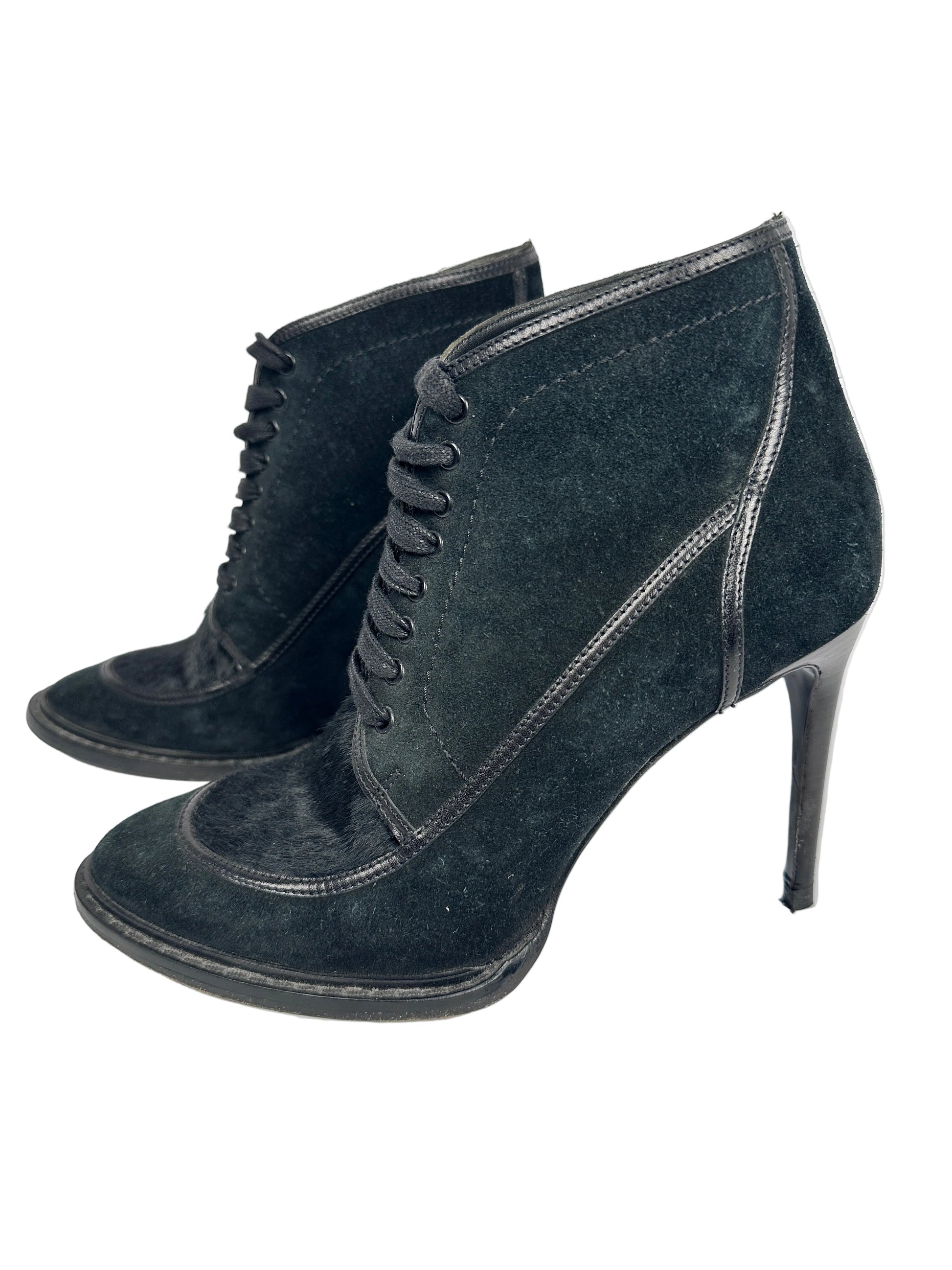 Pair of black suede shoes with decorative elements on a white background