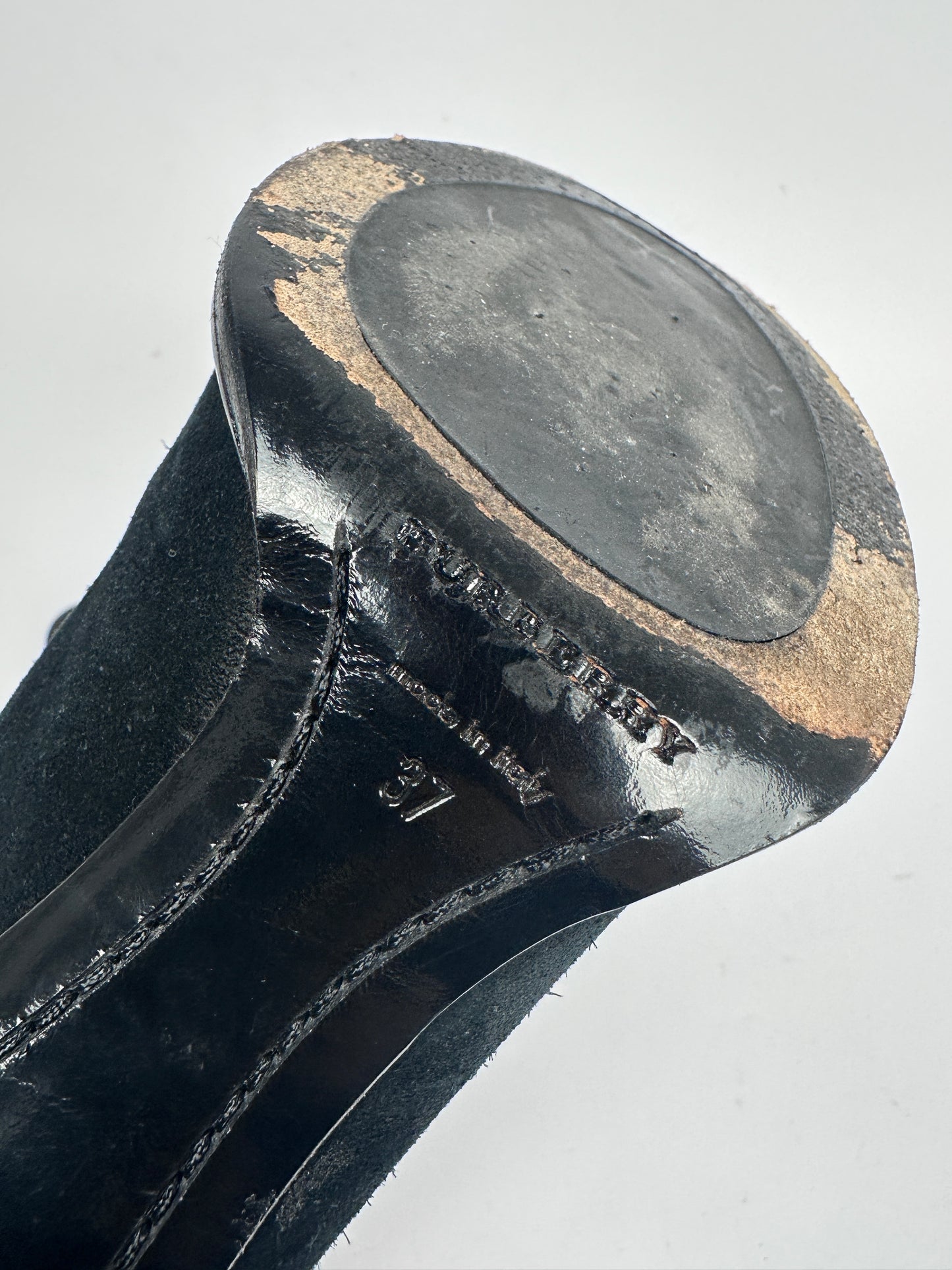 Close-up of a black metal object with gold accents on a light gray background