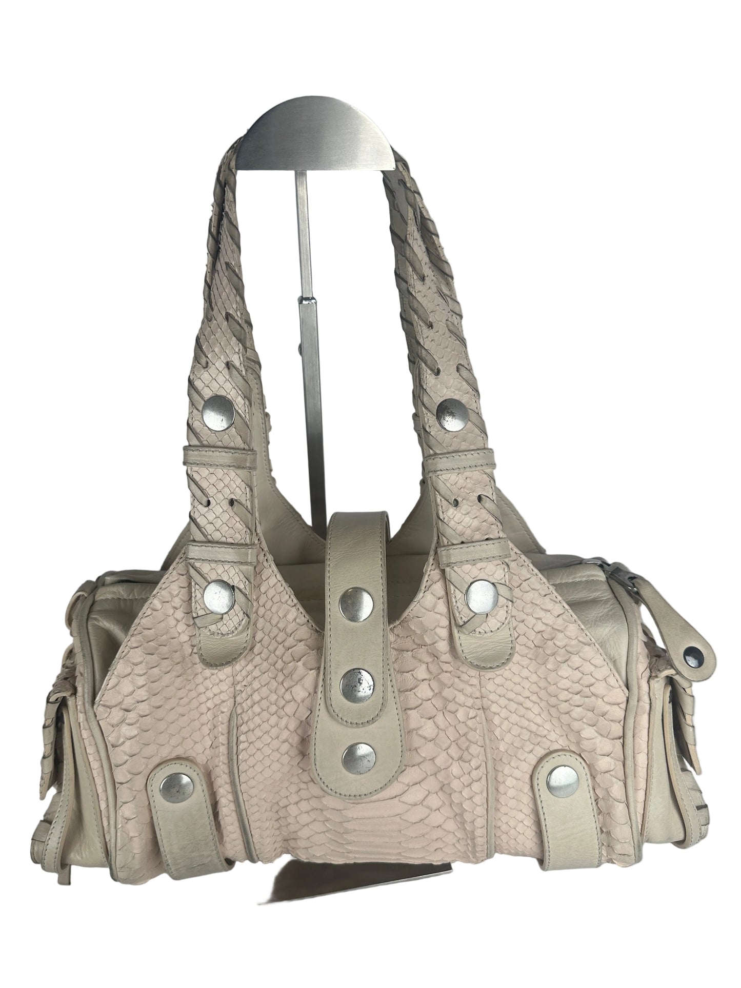 A light beige textured handbag with a braided shoulder strap and silver-tone metal studs, displayed on a metal hanger against a plain gray background.
