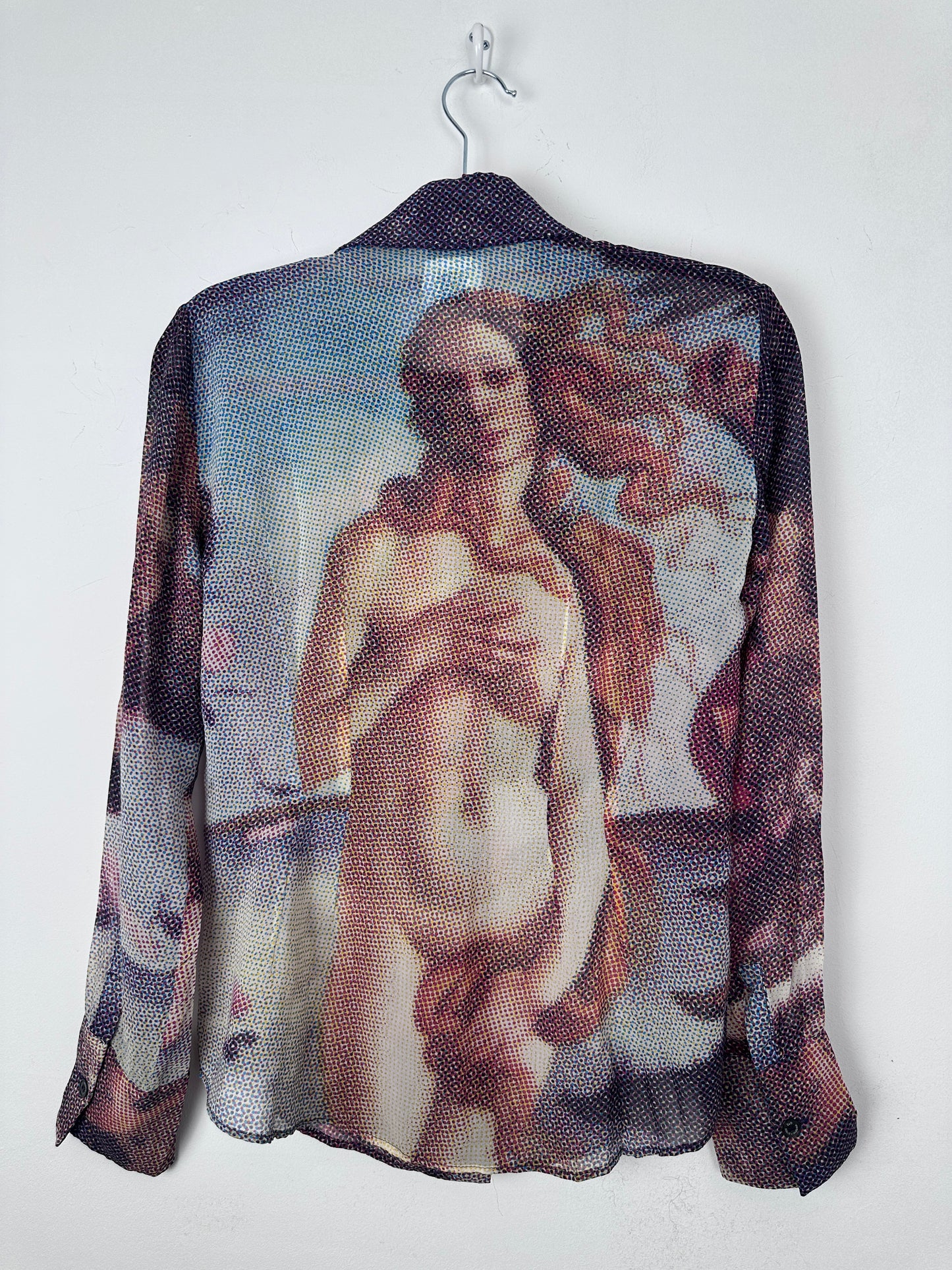 A sheer mesh shirt featuring a printed classical painting of a nude female figure, draped over a black hanger against a plain white background.