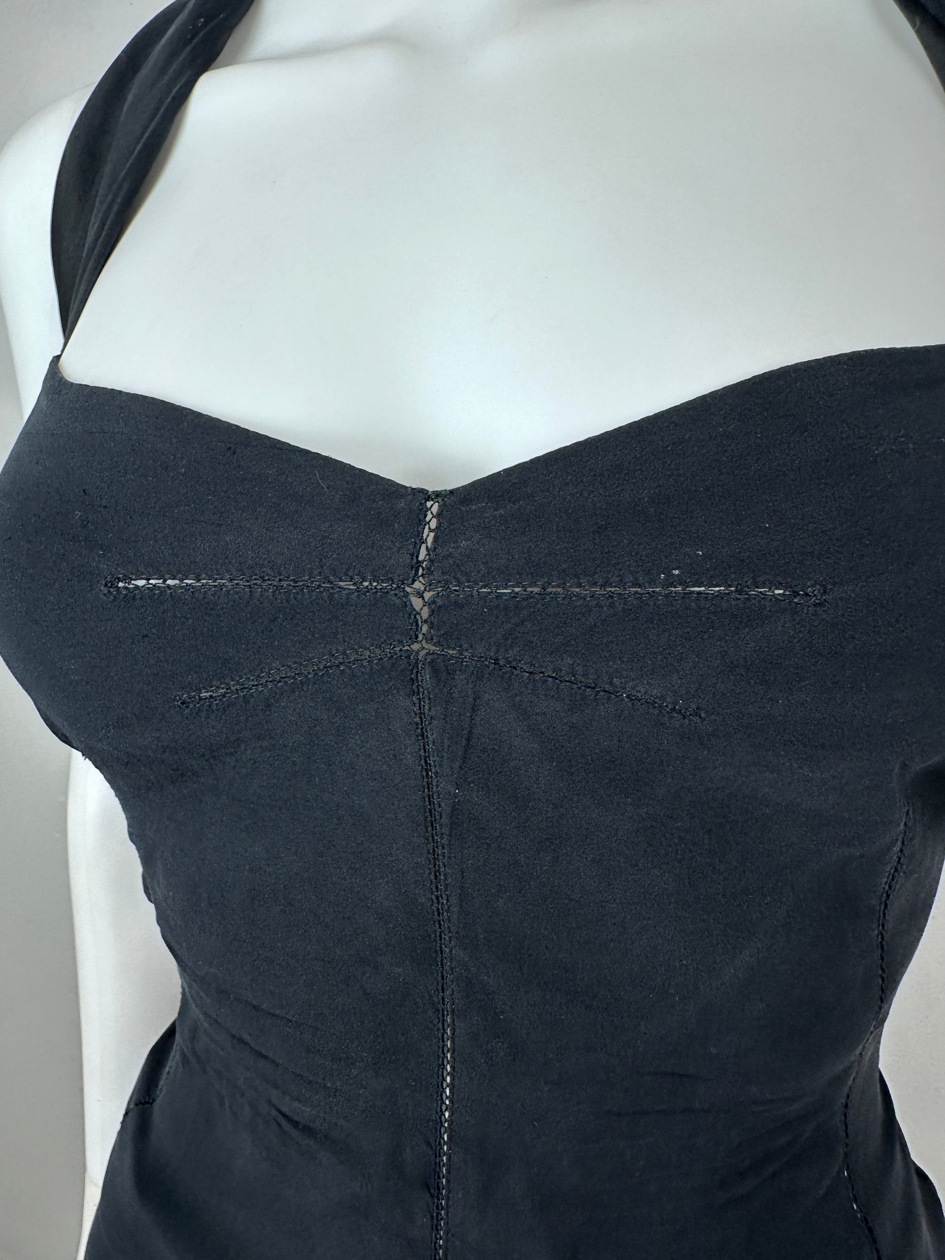 Close-up of the back of a black strapless dress or bodysuit displayed on a white mannequin torso, showing seam details and a V-shaped back cut.