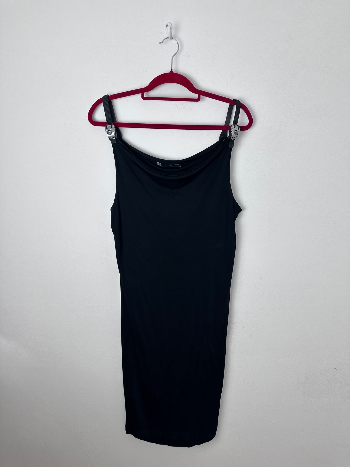 A black sleeveless top or dress laid flat on a white background, hanging from a red hanger.