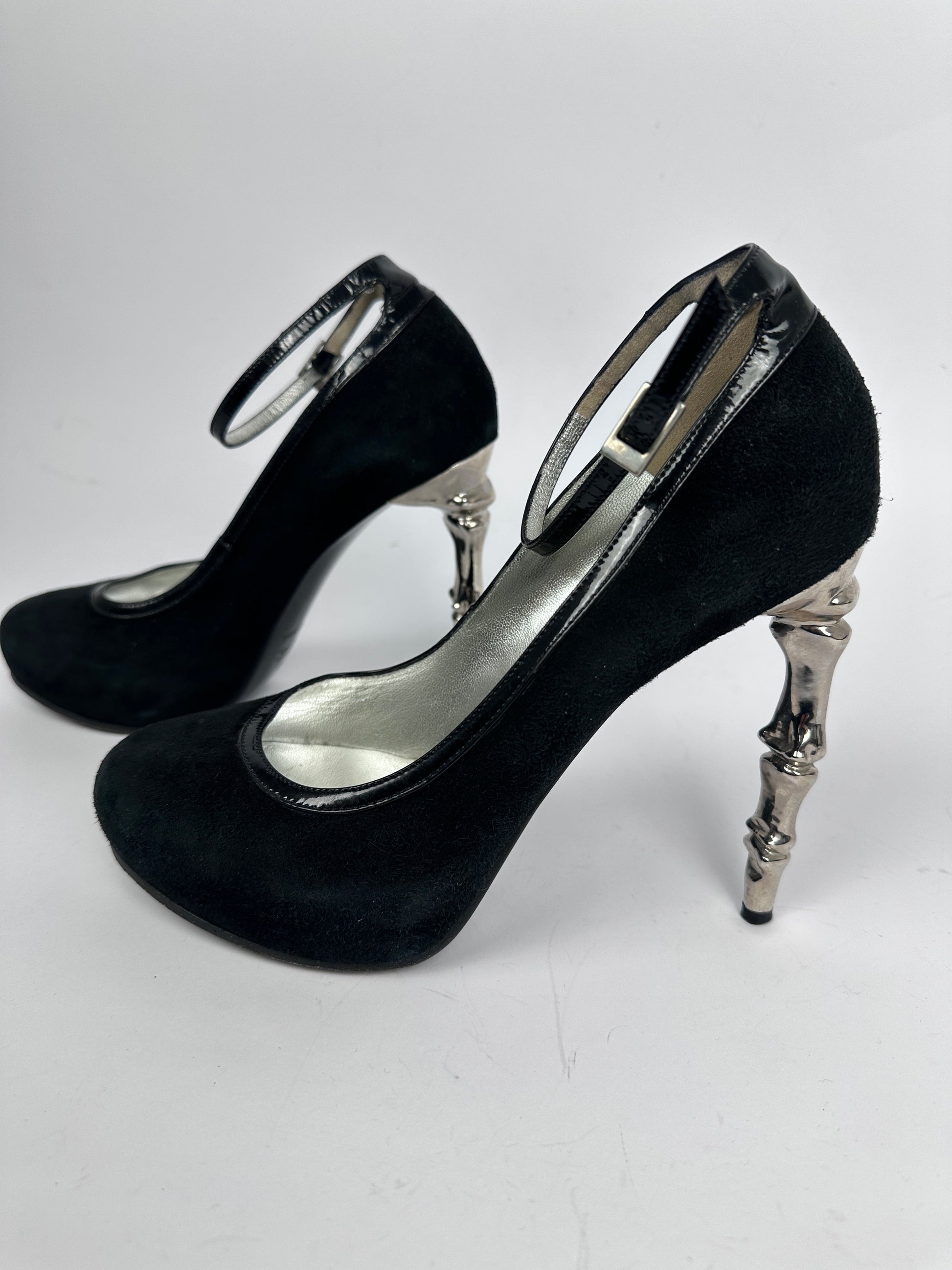 Black high-heeled shoes with silver accents on a white background