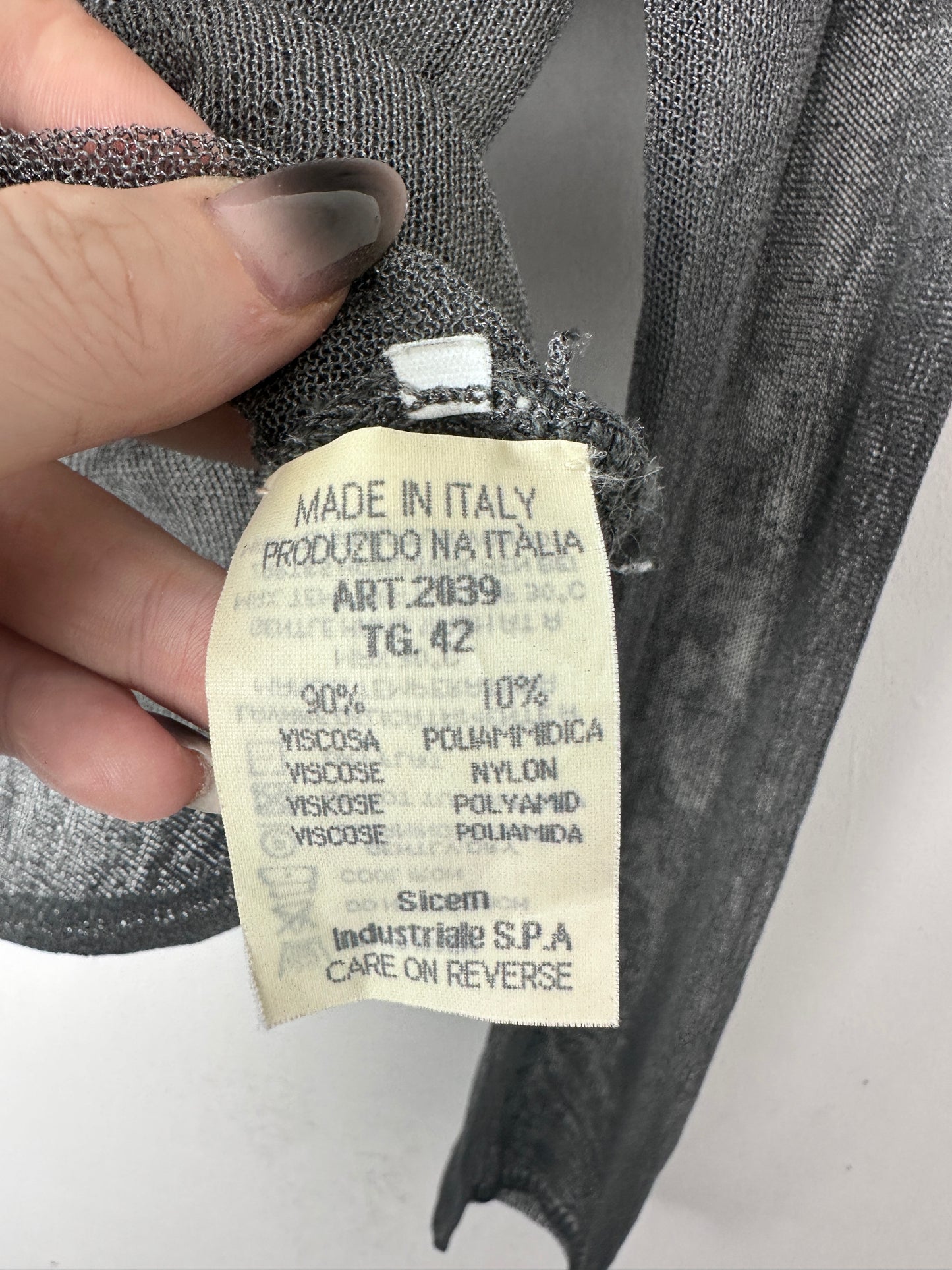 Close-up of a fabric tag with text on a piece of gray fabric.