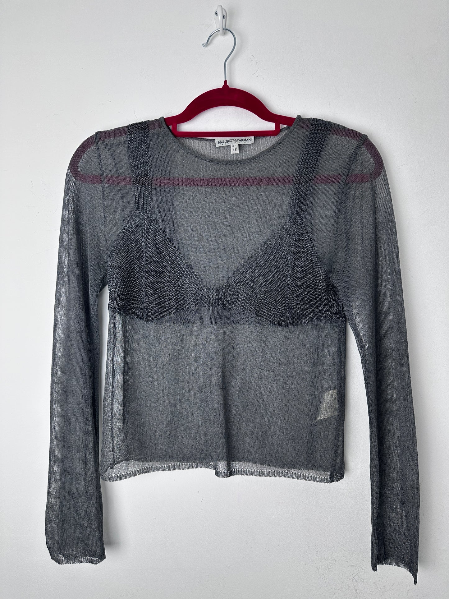 Gray mesh garment on a hanger against a white background