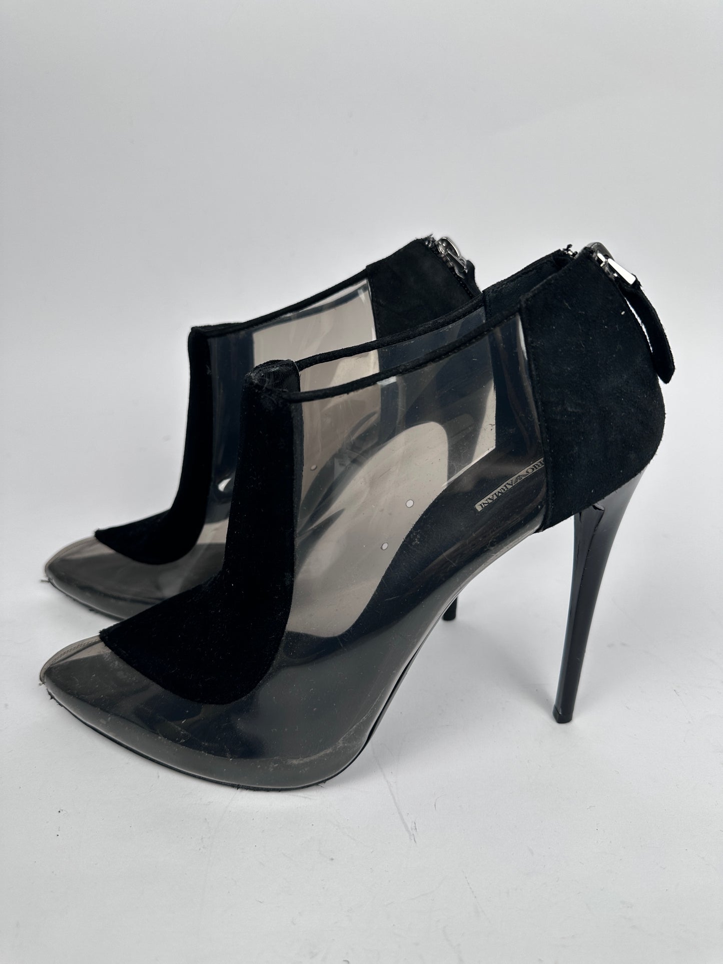 Black high-heeled shoes with clear plastic panels on a white background