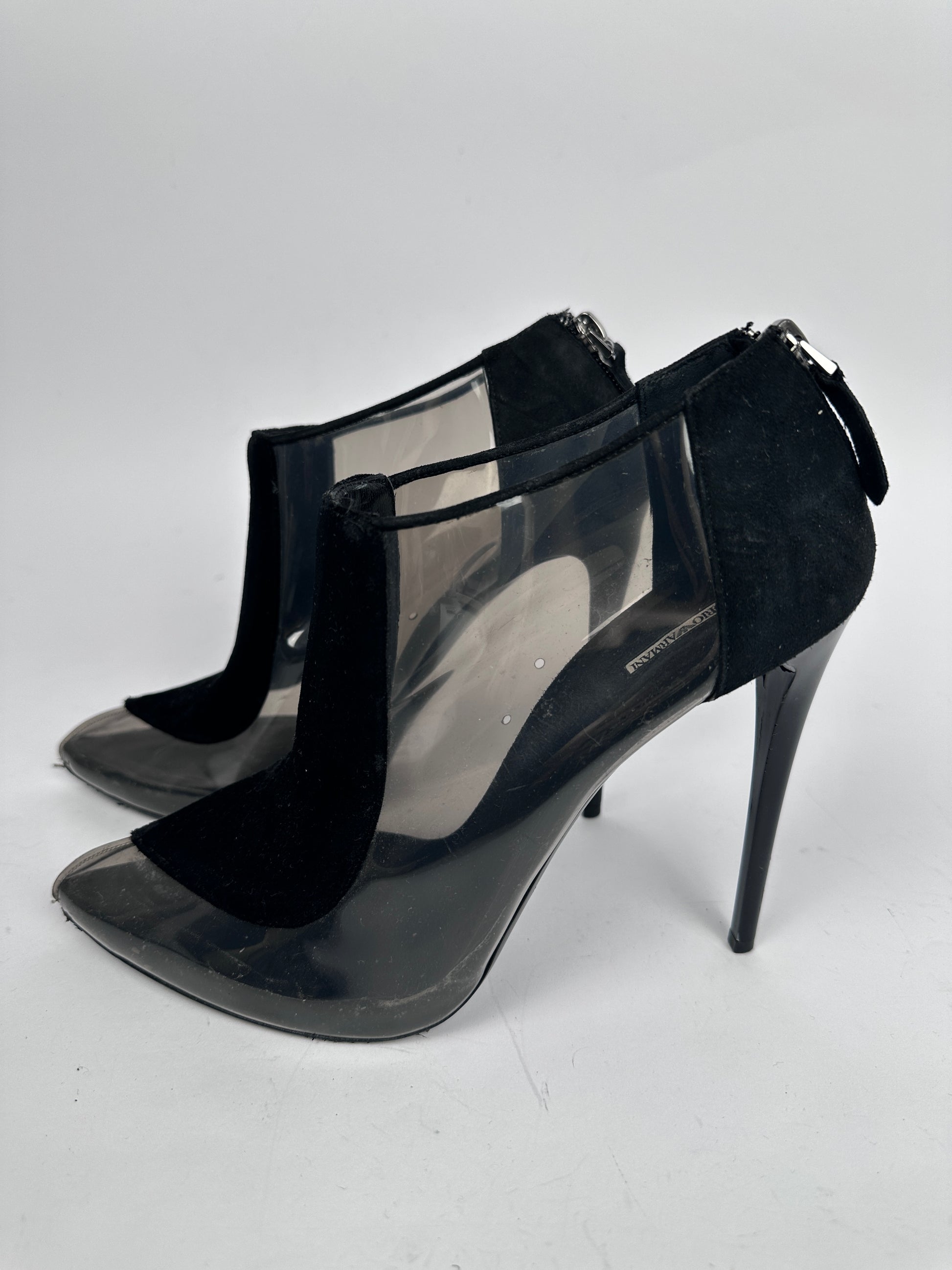 Black high-heeled shoes with clear plastic panels on a white background