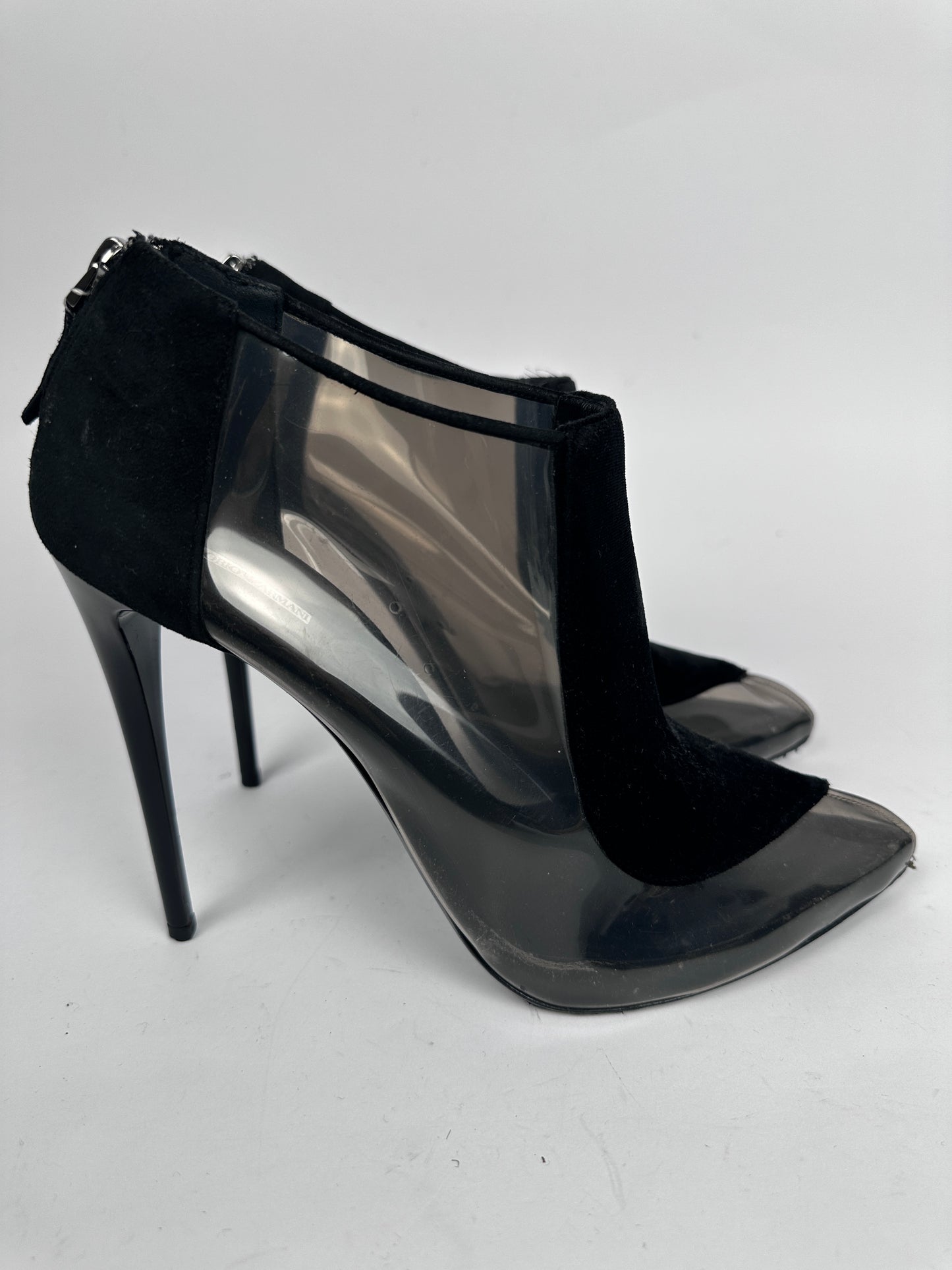 Black high-heeled shoe with sheer overlay on a white background