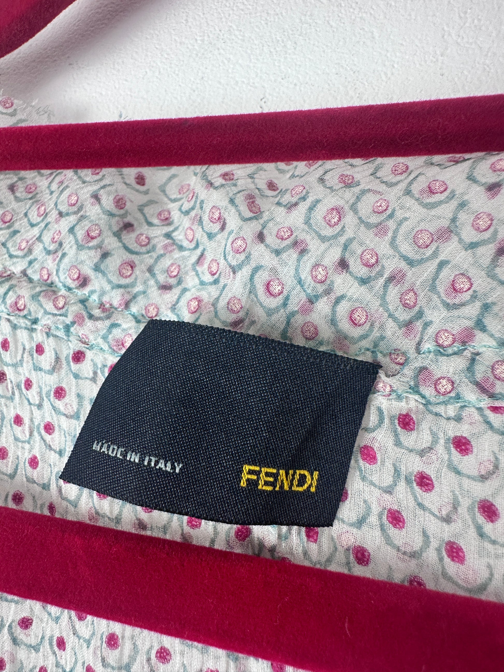 Close-up of a Fendi handbag interior showing a patterned lining with pink and teal floral motifs, a dark navy Fendi label with yellow text, and deep magenta velvet trim.