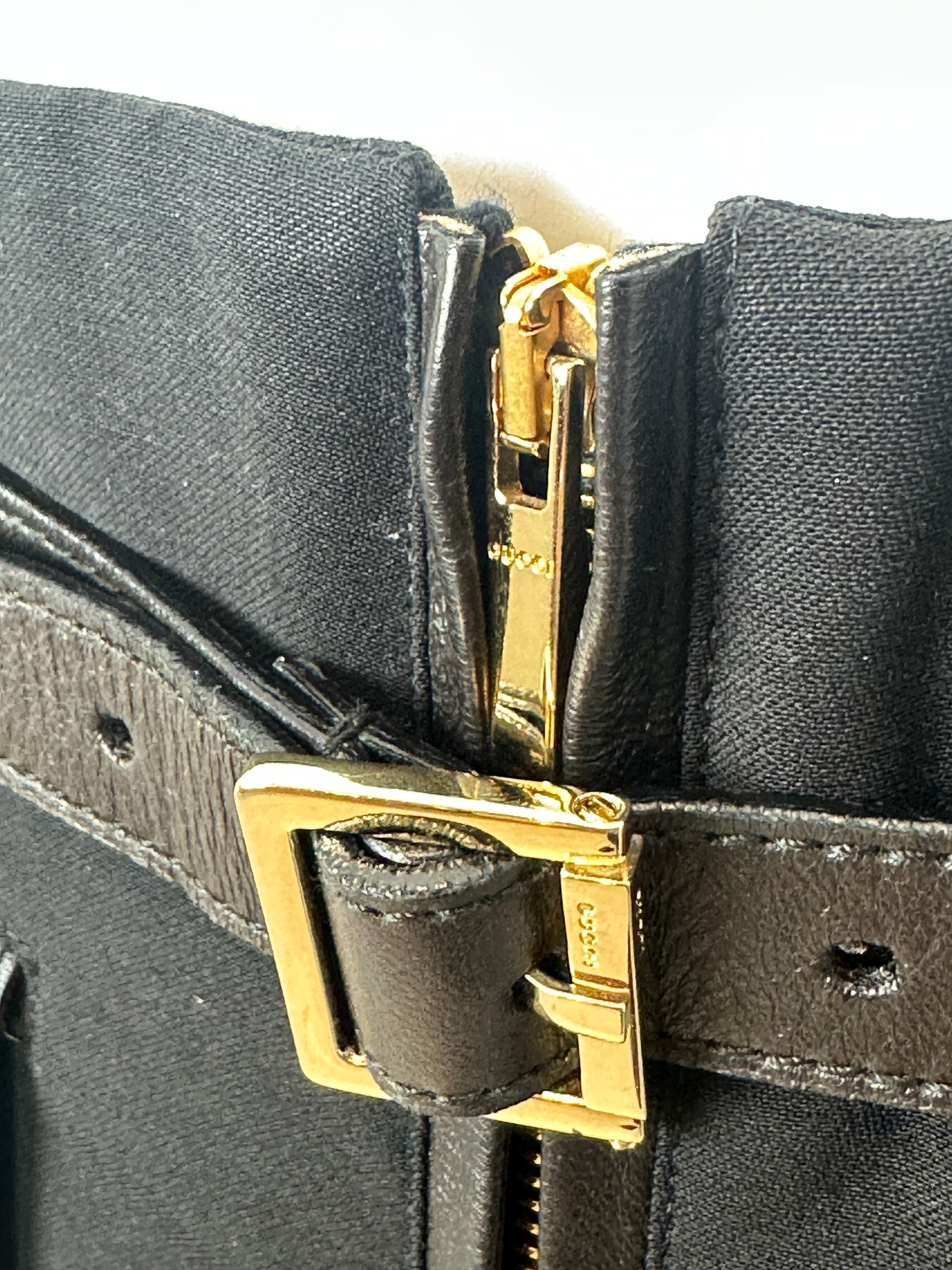 Close-up of a black skirt with gold hardware on a white background