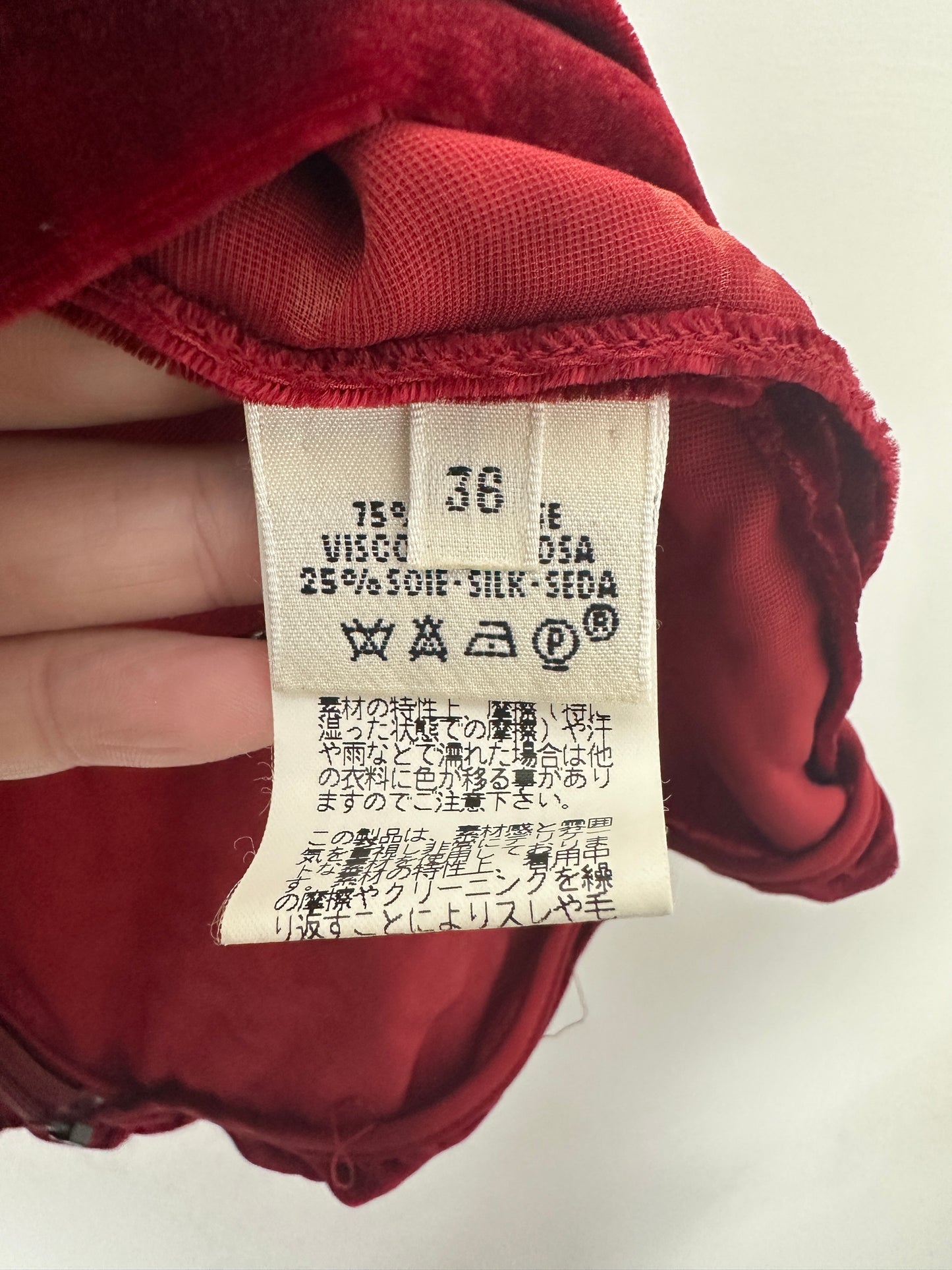 Clothing tag on a red garment with visible text and numbers.
