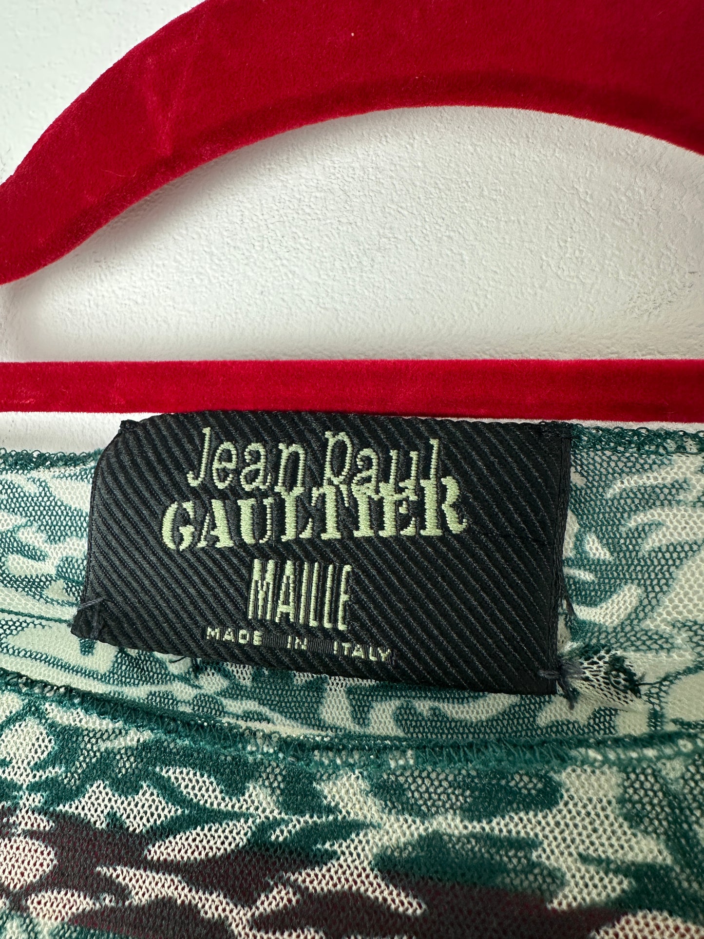 Close-up of a Jean Paul Gaultier label on a garment with red and white background