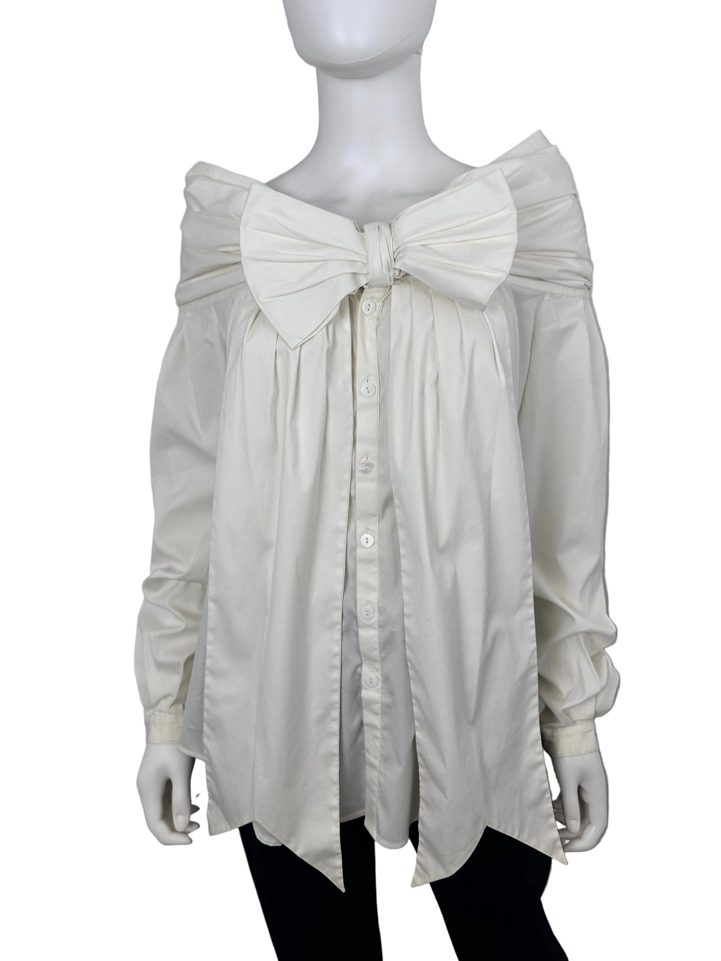 An oversized white long-sleeve shirt dress with a large bow at the waist and a button-down front, displayed on a white mannequin against a light gray background.