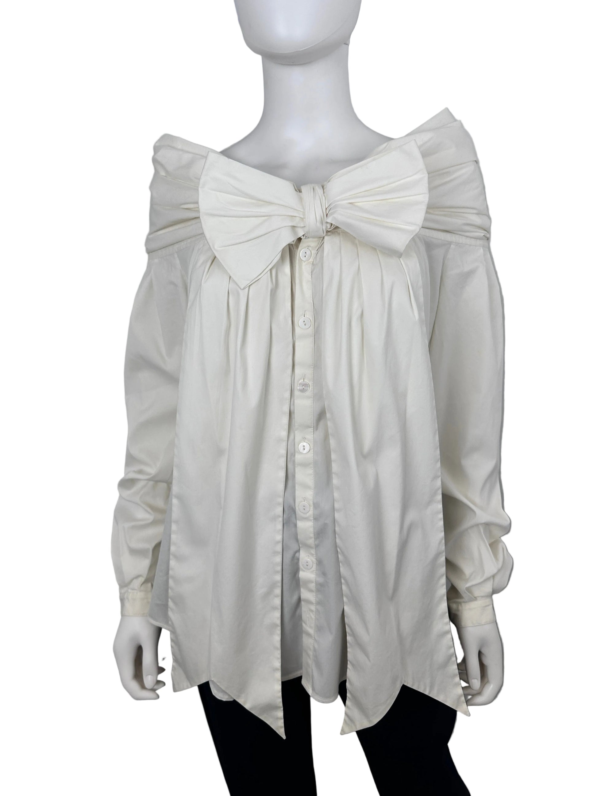 An oversized white long-sleeve shirt dress with a large bow at the waist and a button-down front, displayed on a white mannequin against a light gray background.