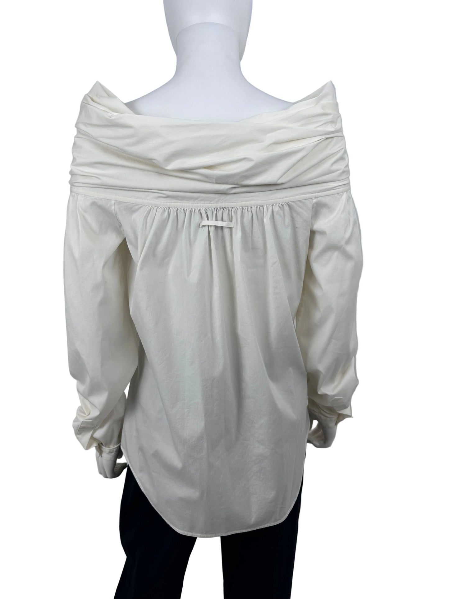 An off-white puff-sleeve blouse with a gathered waist, displayed on a white mannequin torso against a plain light gray wall.
