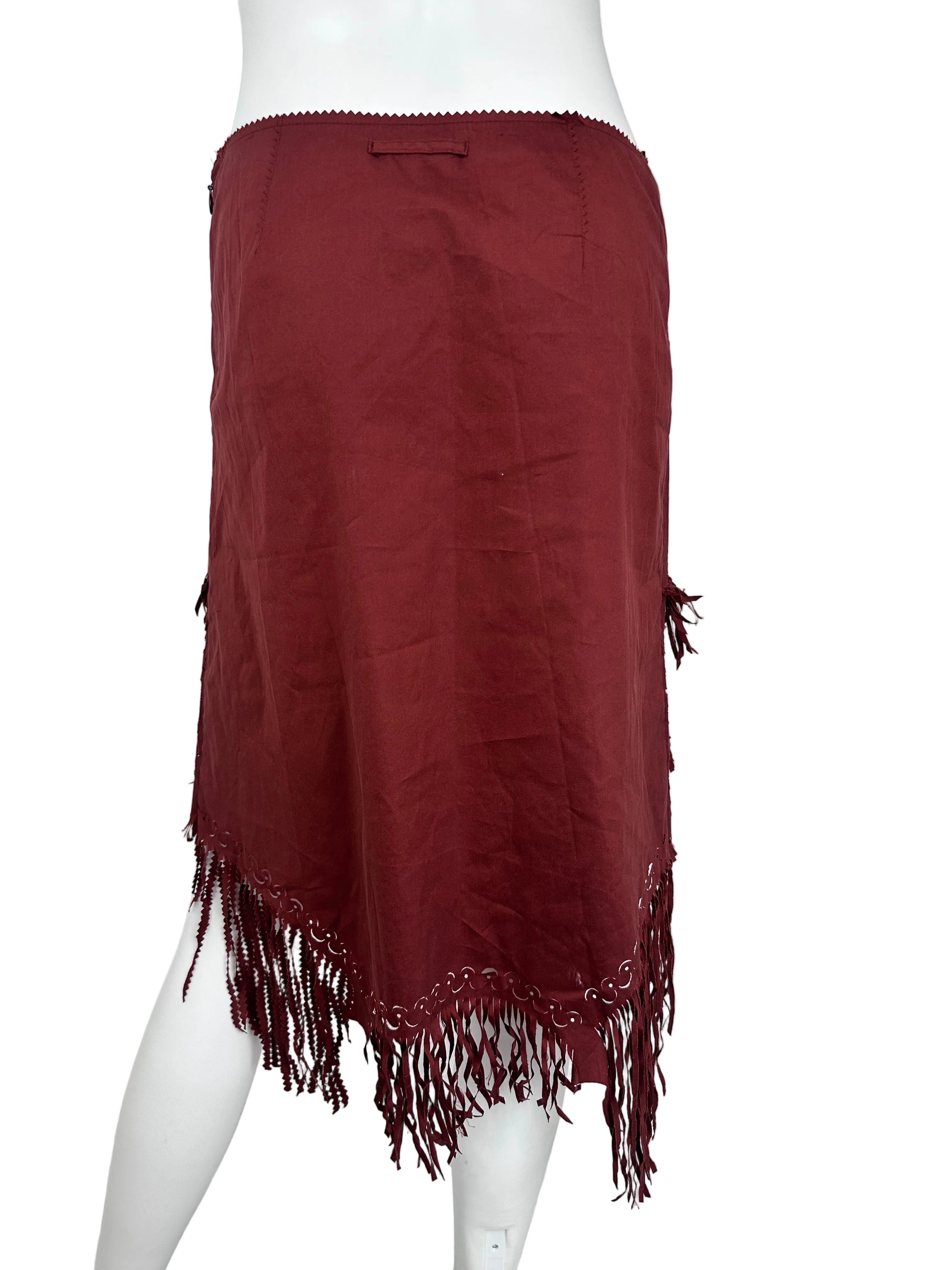 A dark red fringed skirt draped over a white mannequin torso, shown against a plain white wall background.