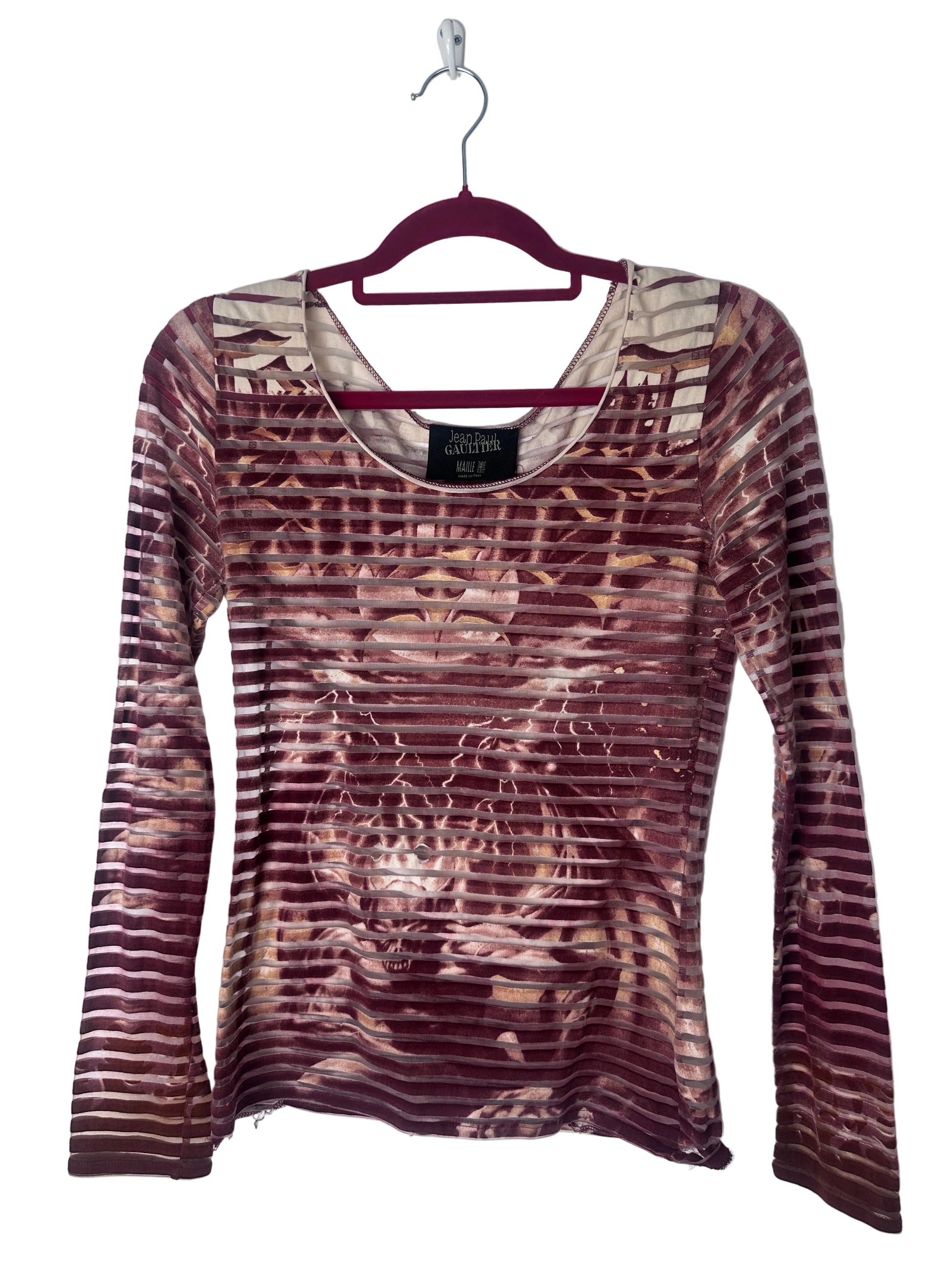 A long-sleeve scoop-neck top by Jean Paul Gaultier, featuring a metallic bronze and burgundy striped pattern with a subtle sheen, hanging on a dark burgundy hanger against a white background.