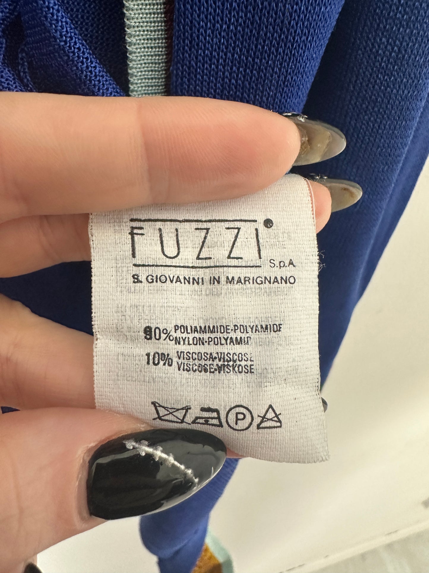 Close-up of a clothing label with 'FUZZI' branding held by a hand.