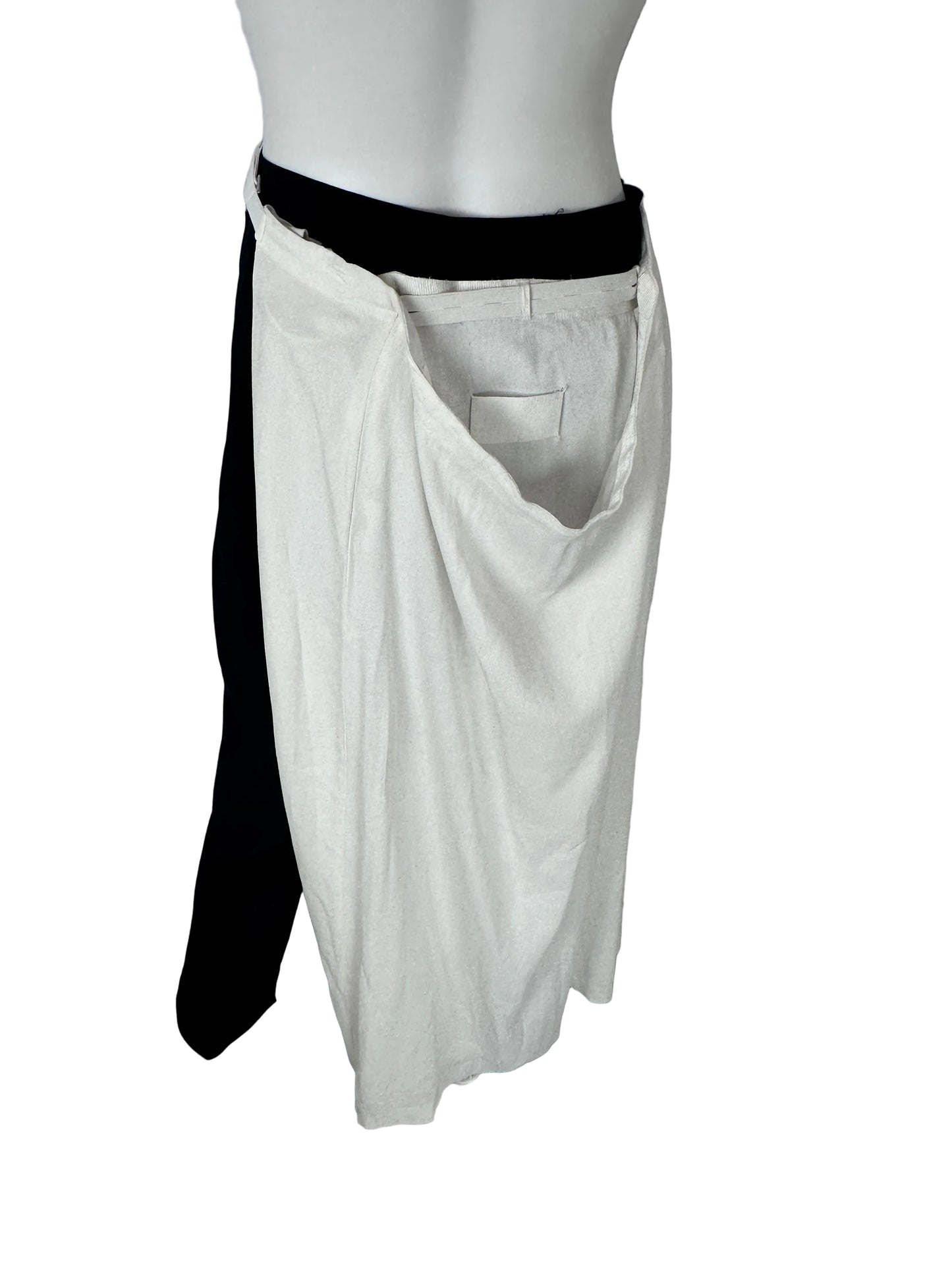A white skirtdisplayed on a mannequin torso, with black leggings or pants layered underneath, photographed indoors against a plain light wall and gray floor.