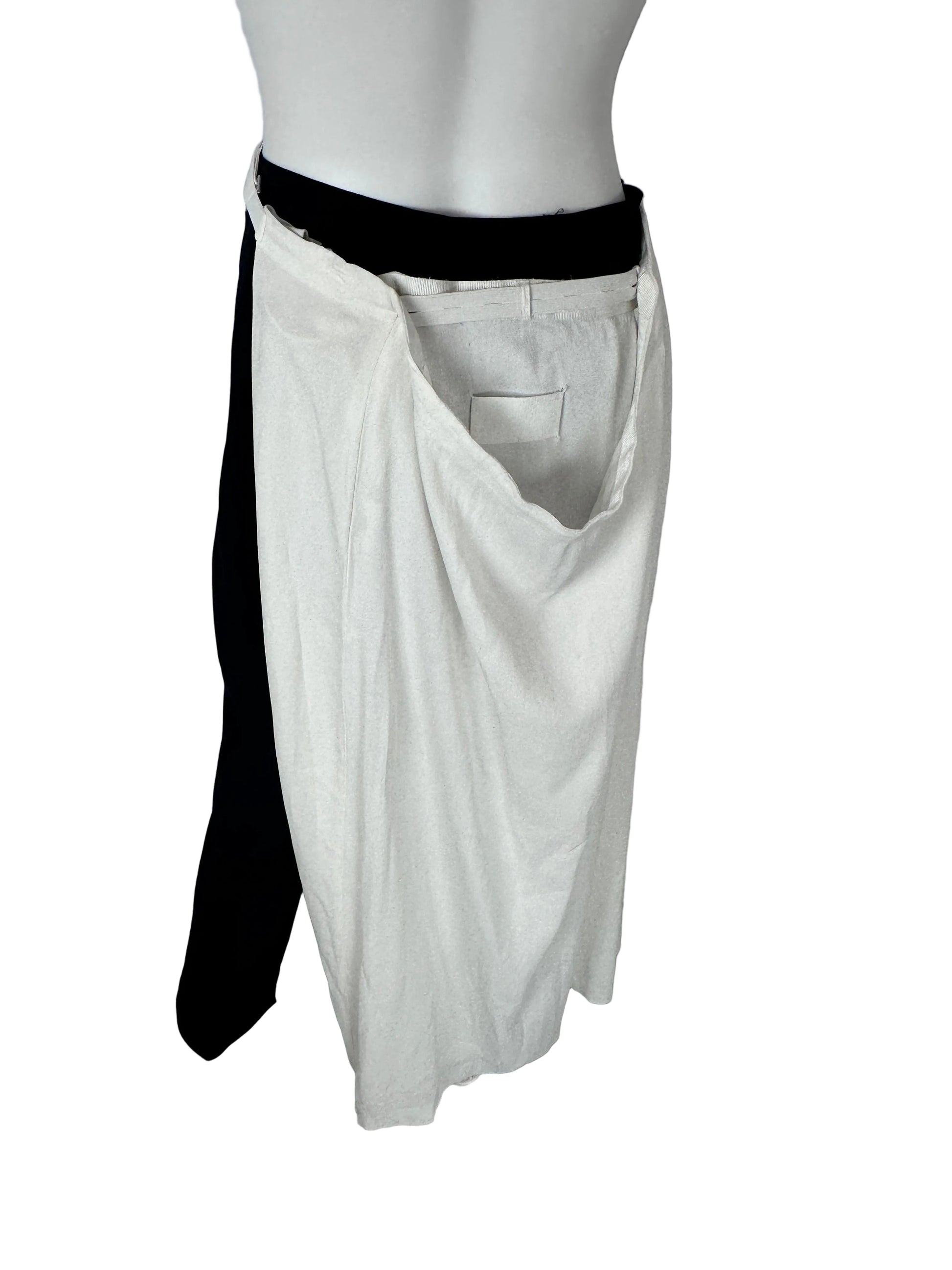 A white skirtdisplayed on a mannequin torso, with black leggings or pants layered underneath, photographed indoors against a plain light wall and gray floor.