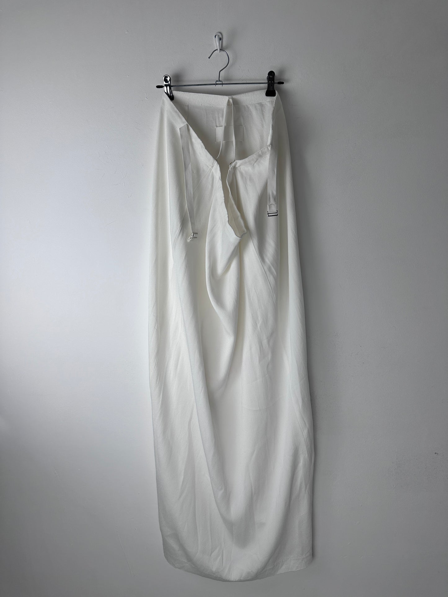 A white skirt with a gathered waist, displayed flat on a metal hanger against a plain light gray background.