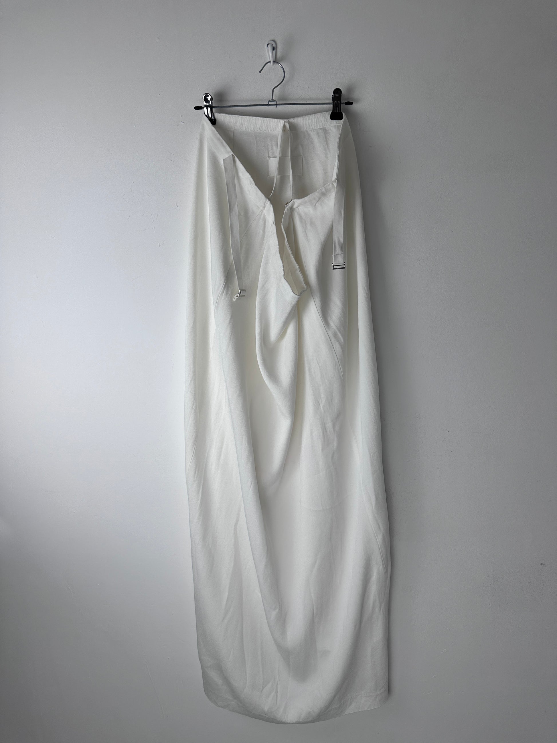 A white skirt with a gathered waist, displayed flat on a metal hanger against a plain light gray background.