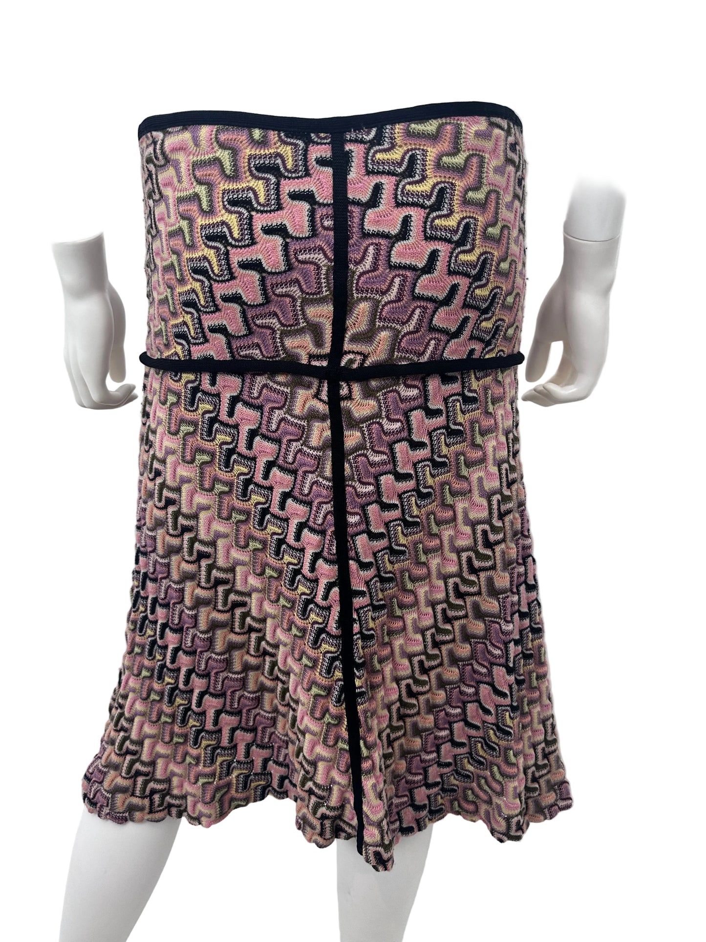 A patterned knit dress displayed on a white mannequin torso, featuring a geometric maze-like weave in pink, purple, black, and beige tones with solid black trim.