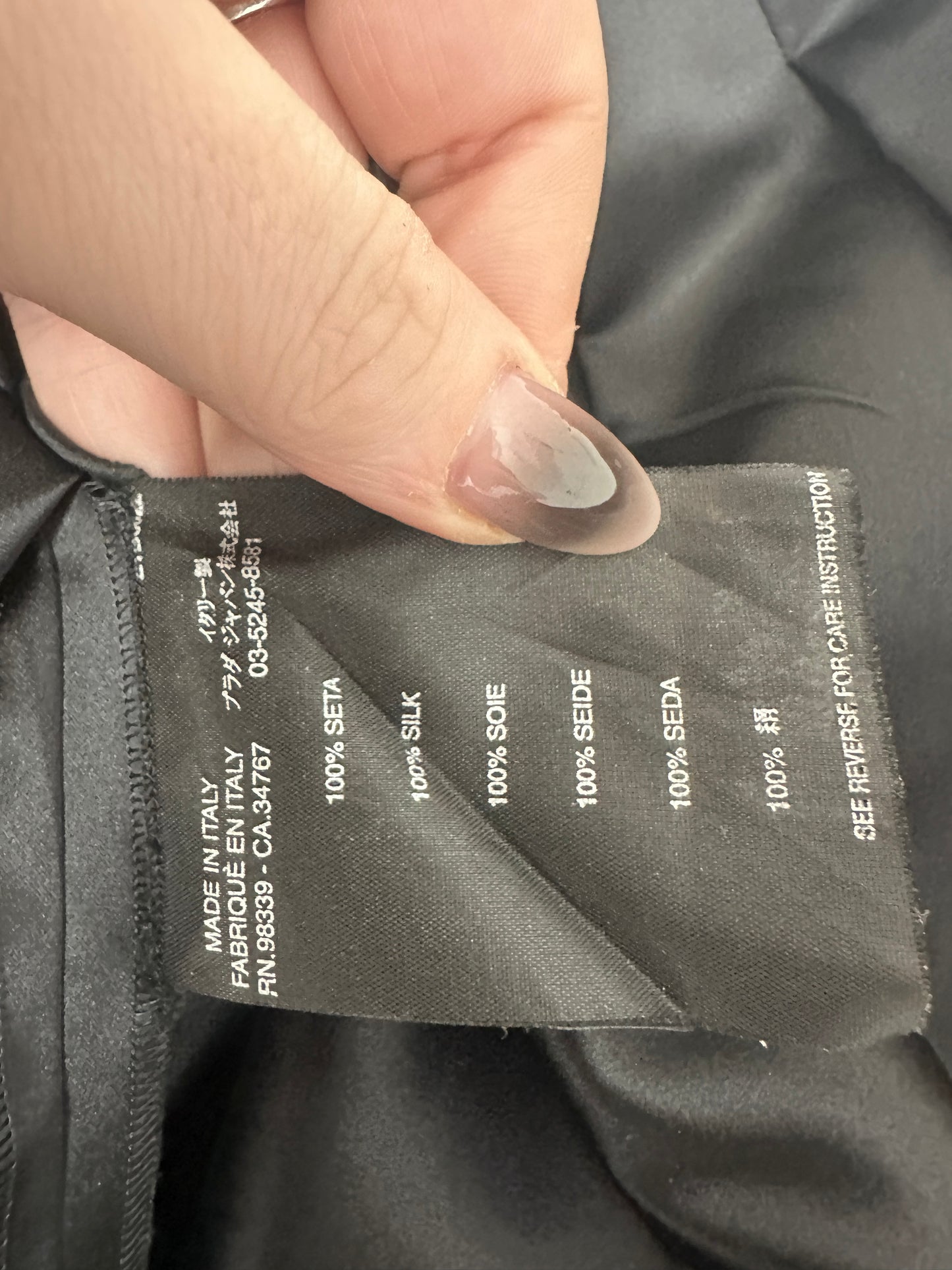 Close-up of a fabric composition label on a garment with a hand holding it.
