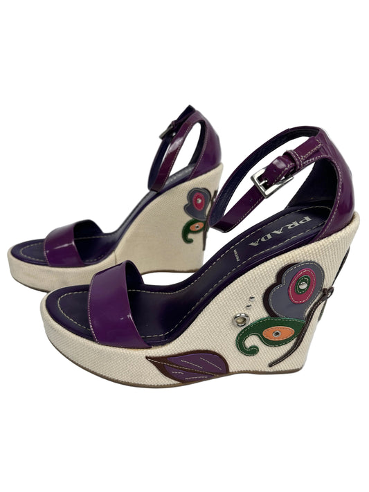 Pair of sandals with purple straps and decorative elements on a light gray background