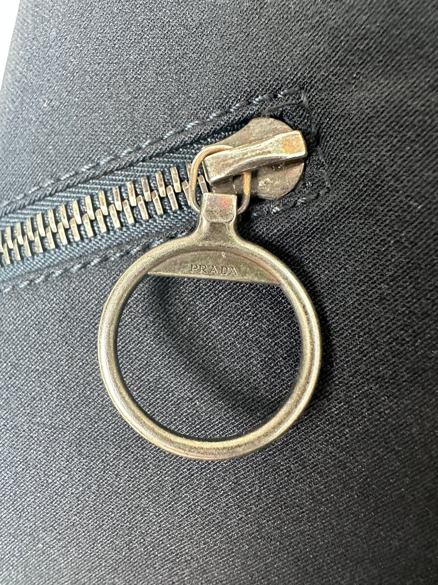 Metal zipper pull on a black fabric background