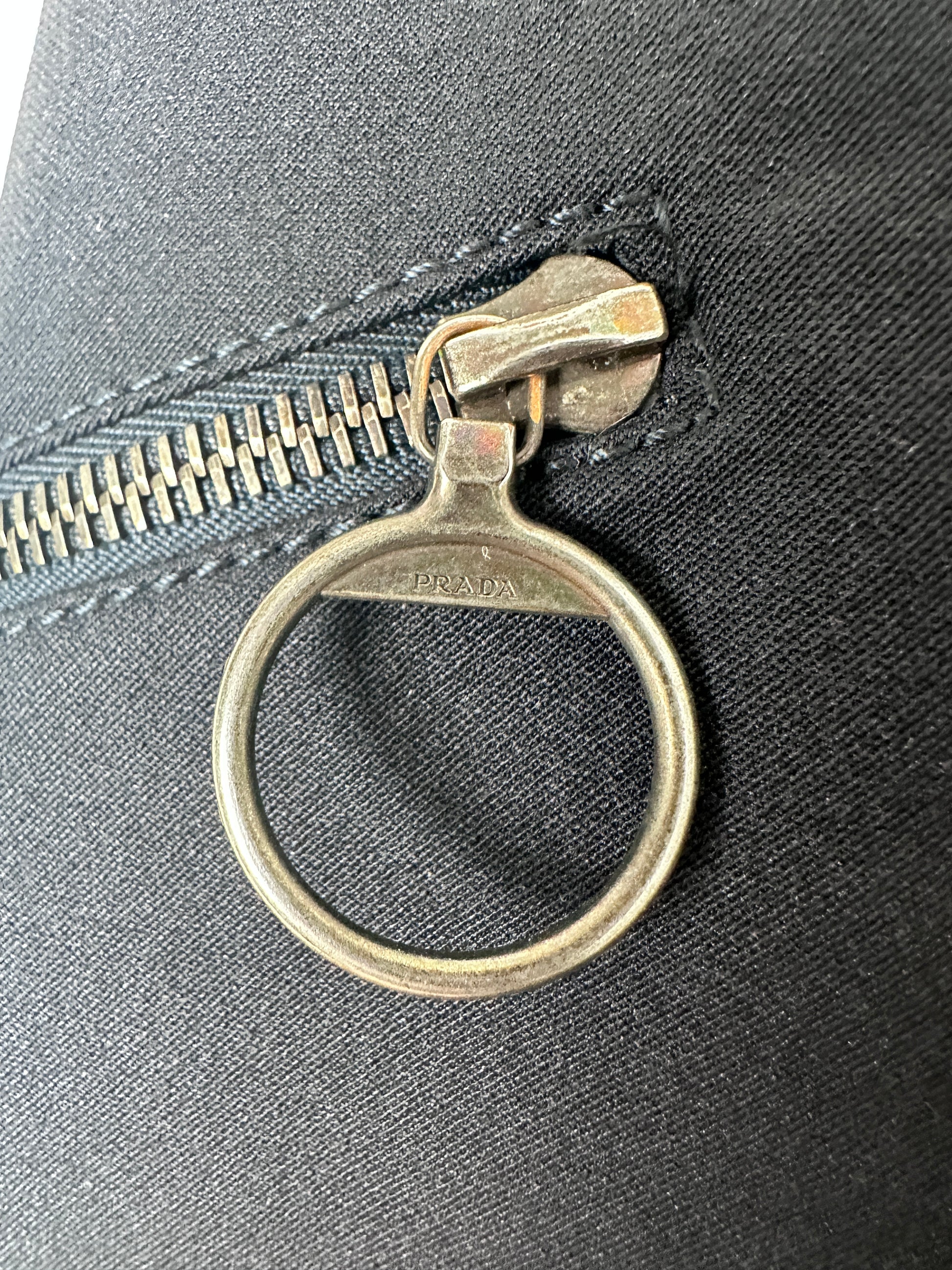 Metal zipper pull on a black fabric background