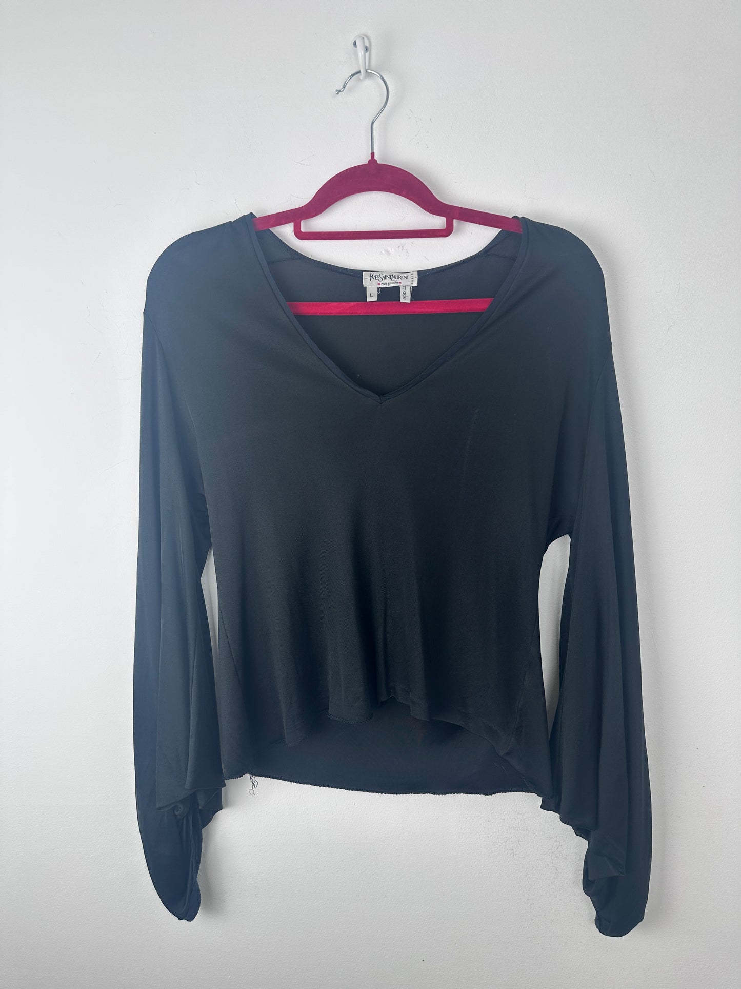 A long-sleeve dark navy blue top with a split neckline and magenta trim, hanging on a magenta hanger against a light gray background.